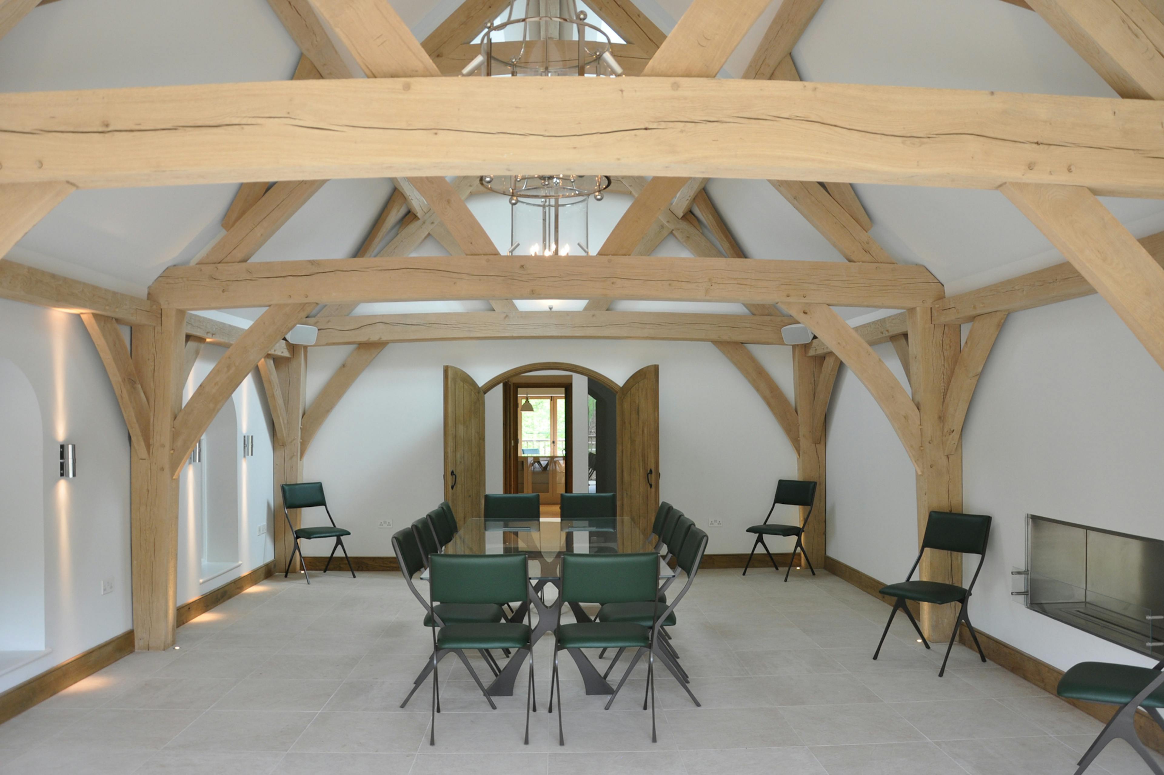 A table and chairs in an oak framed room with three trusses 