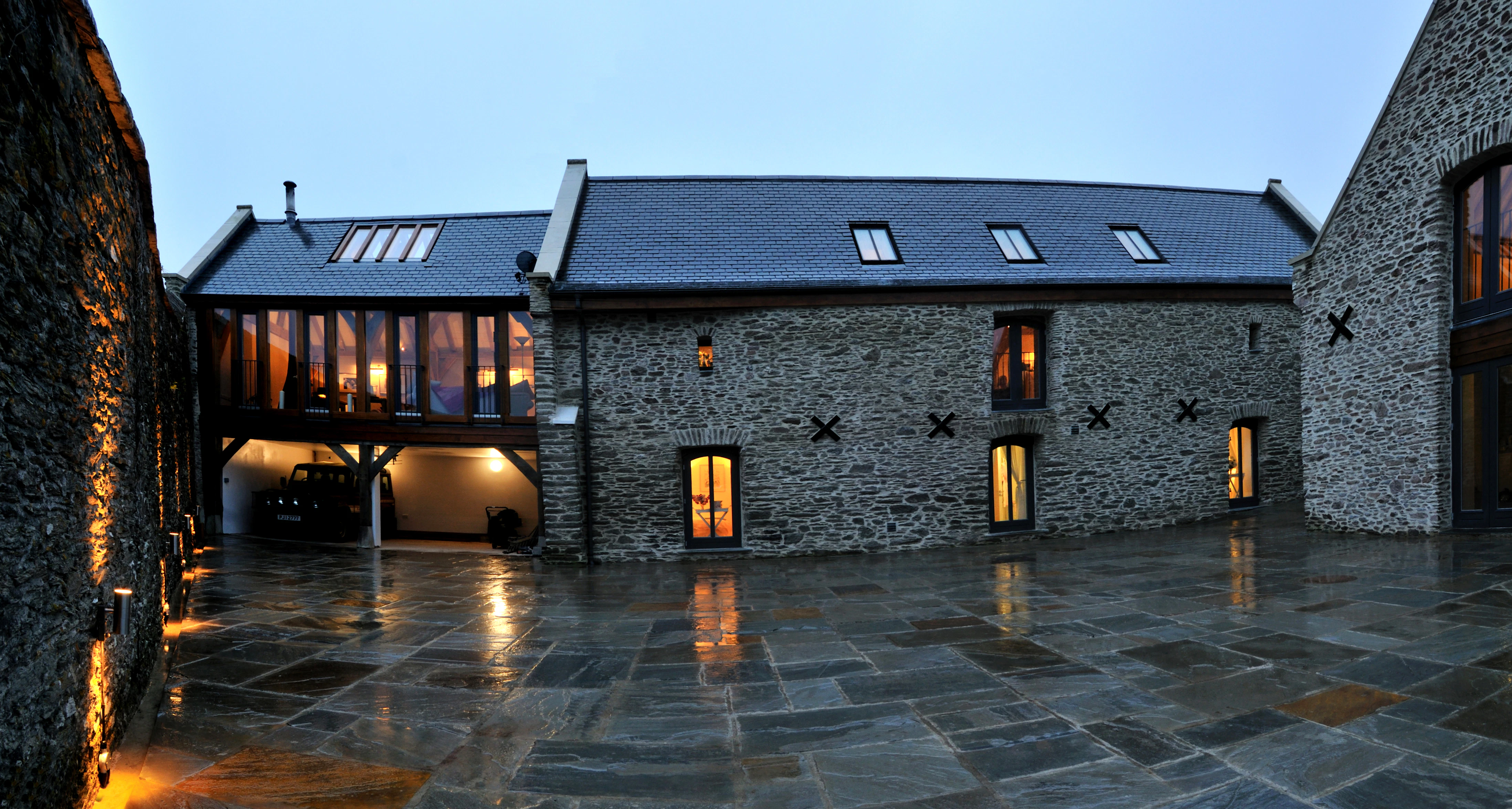 At dusk light shines from the windows of a stone clad barn converted to a home