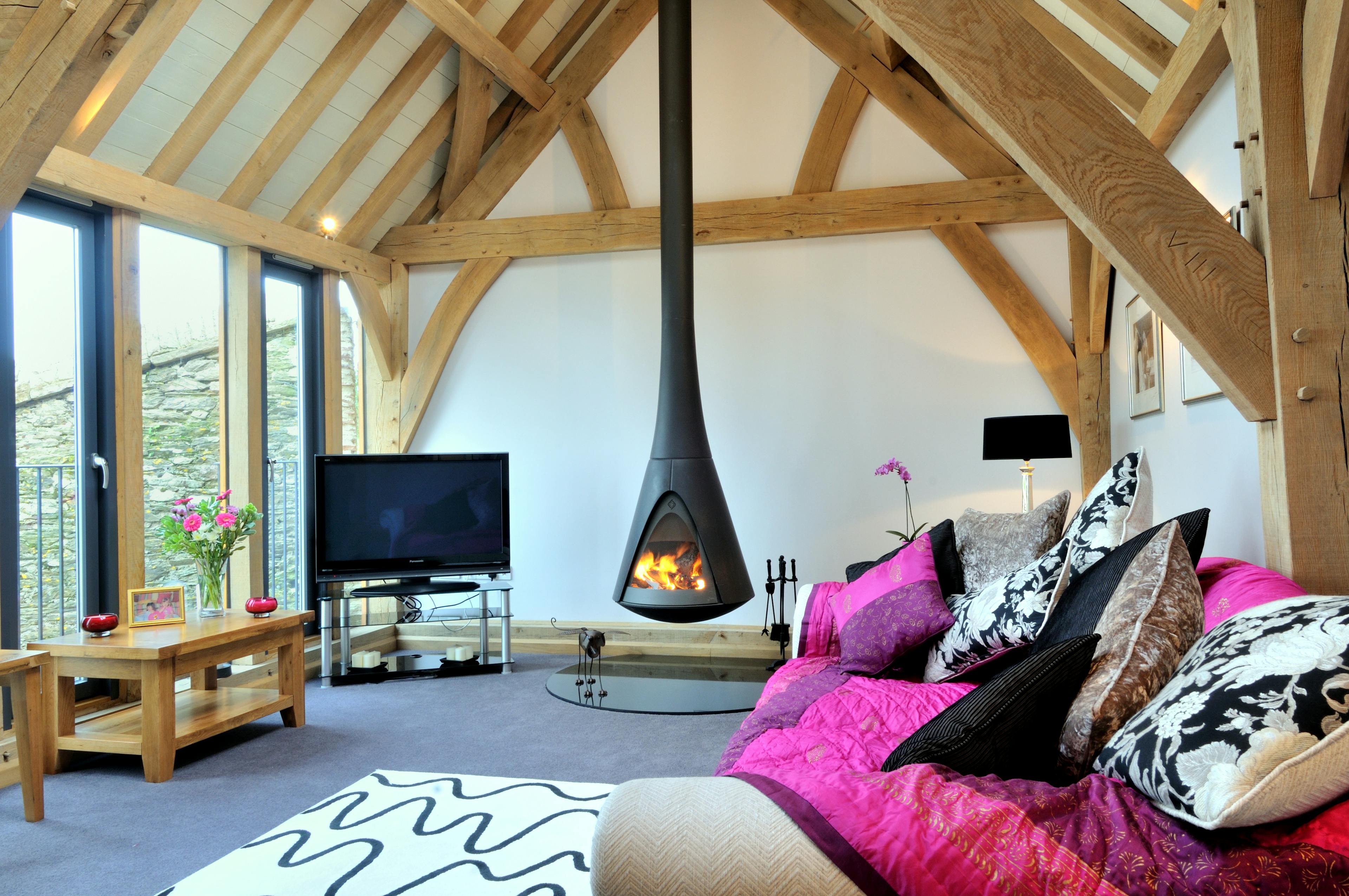 An oak framed sitting room with sofas, wooden side tables and a black log burner