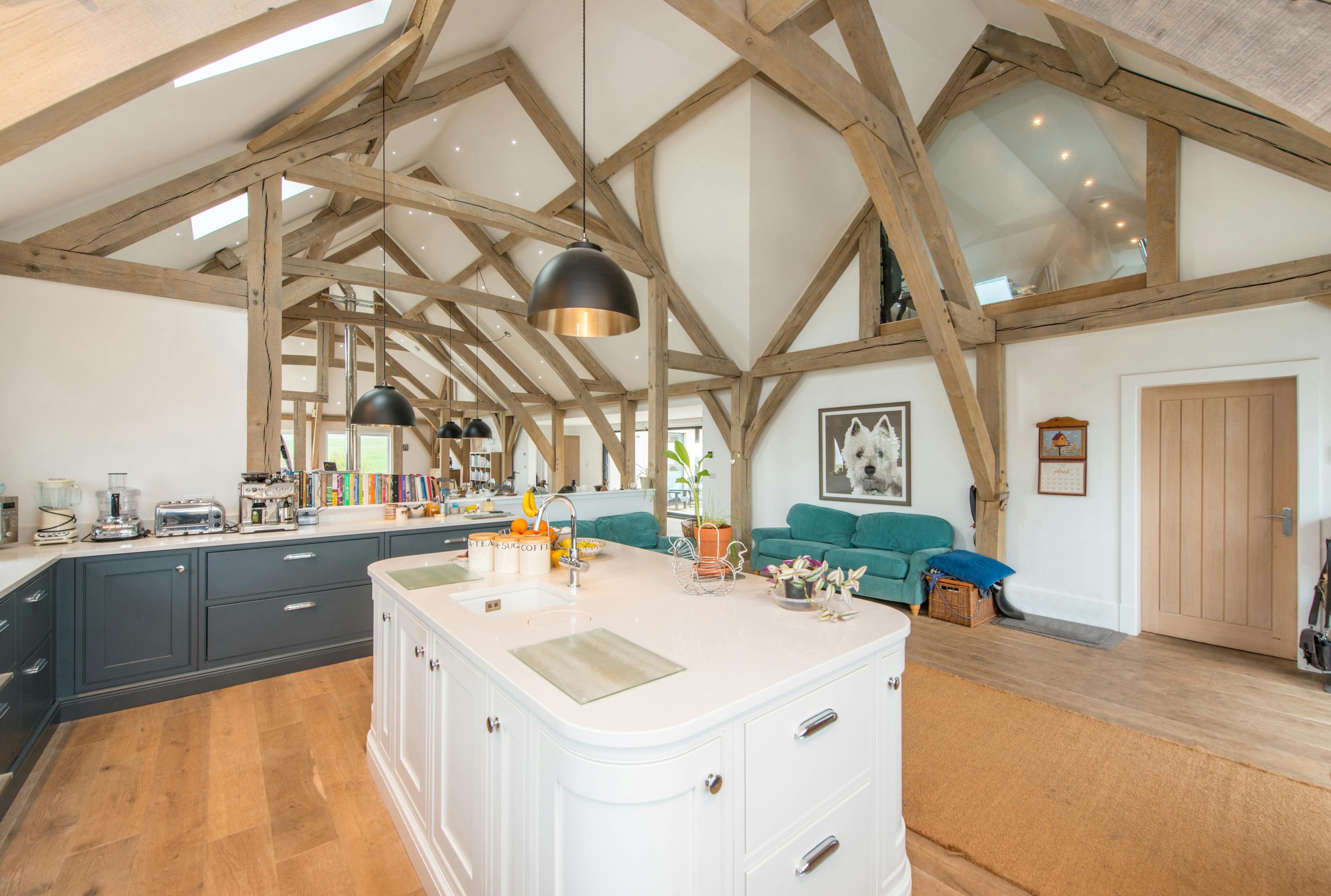 A vaulted oak framed open plan kitchen and living room with a white painted island