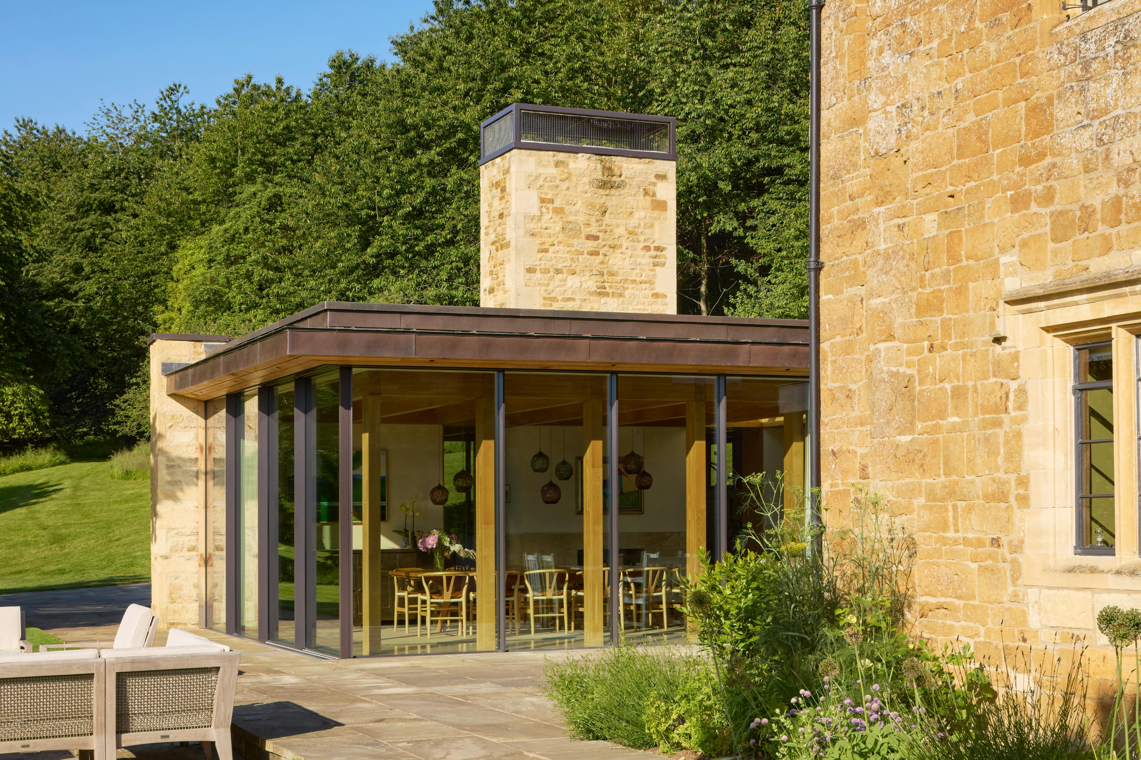 Exterior of an oak glulam extension to a listed manor house with a landscaped garden