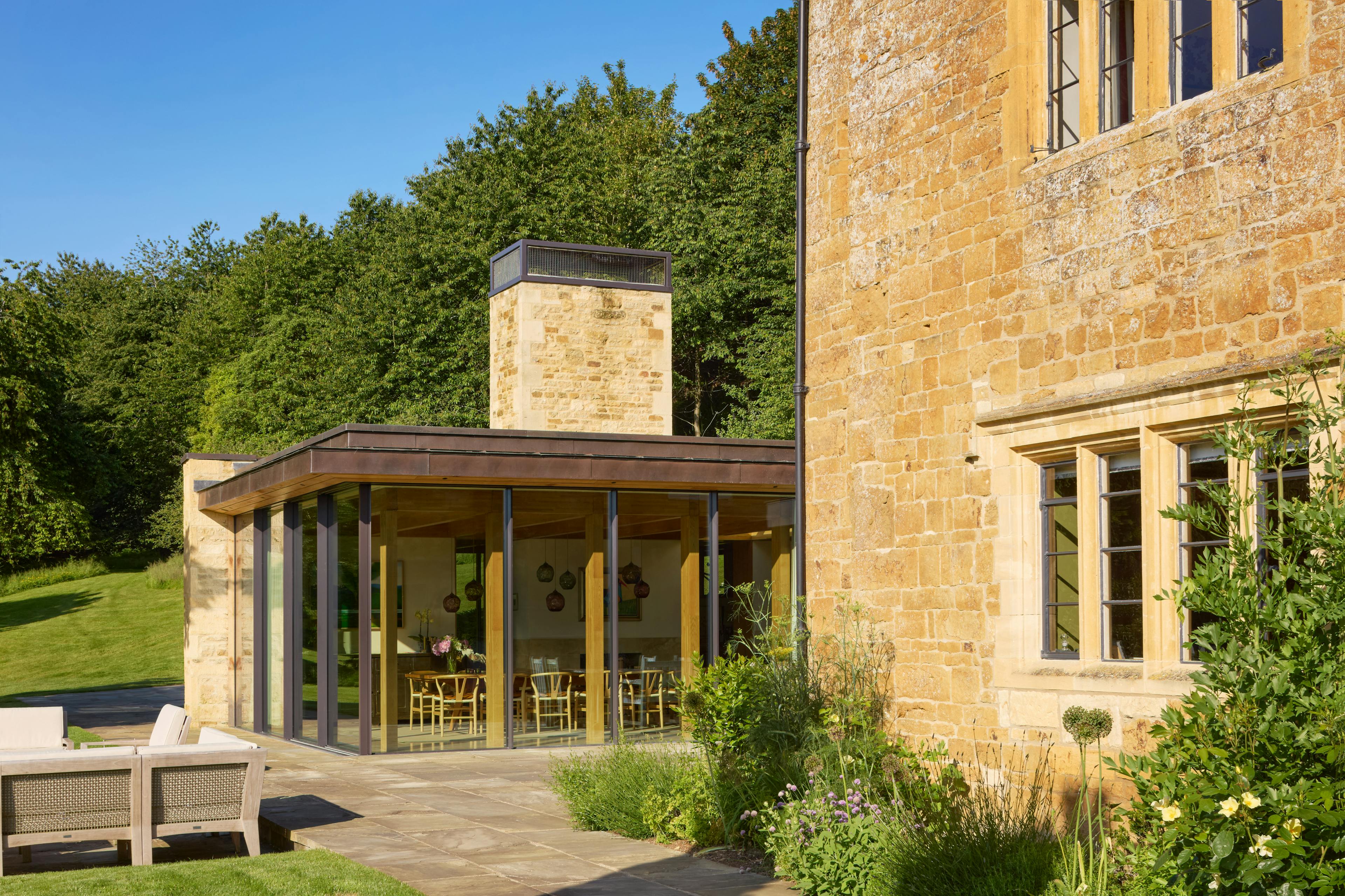 Exterior of an oak glulam extension to a listed manor house with a landscaped garden