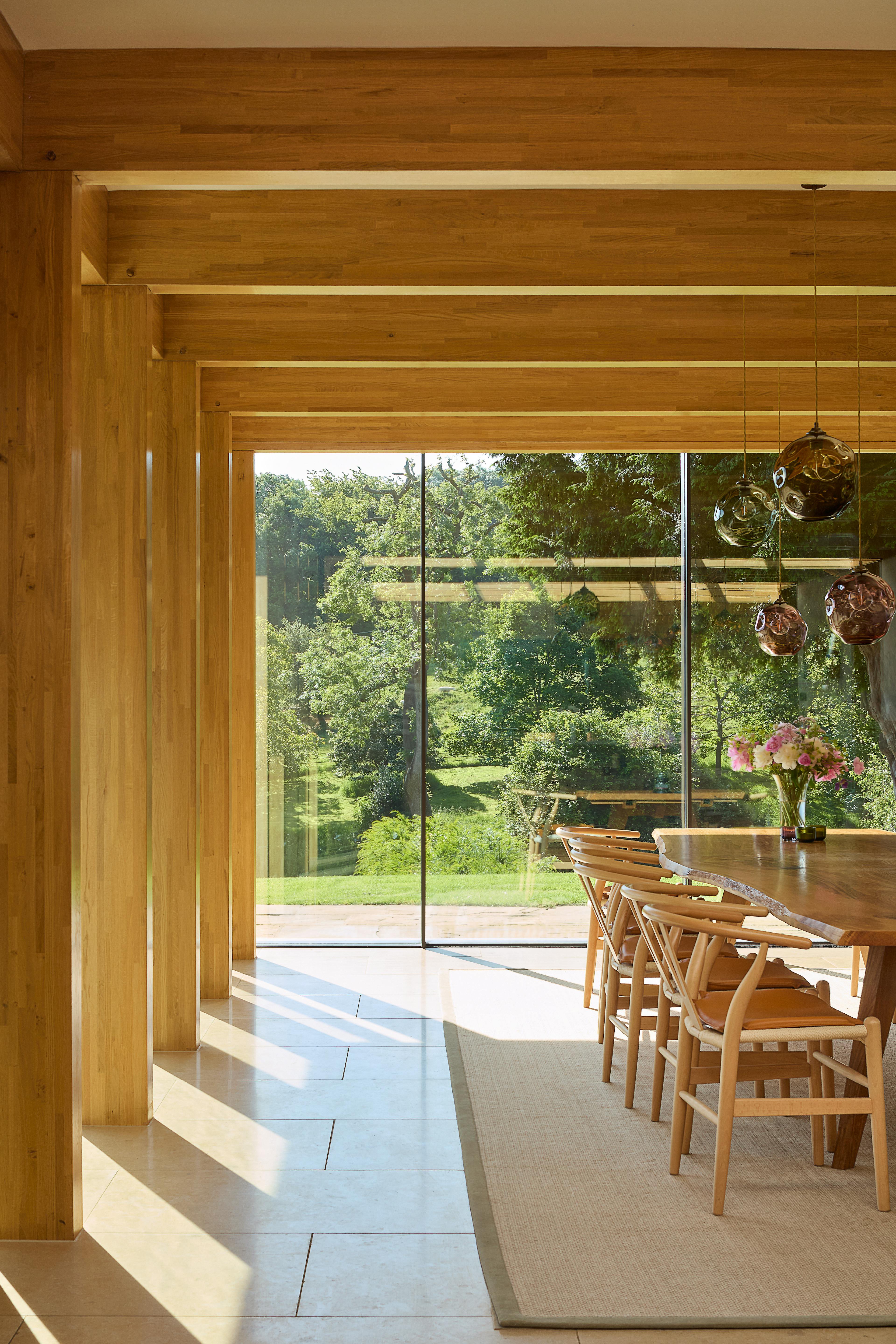 The formal dining area of an oak glulam extension to a listed manor house sunlight coming through with large screen glazing