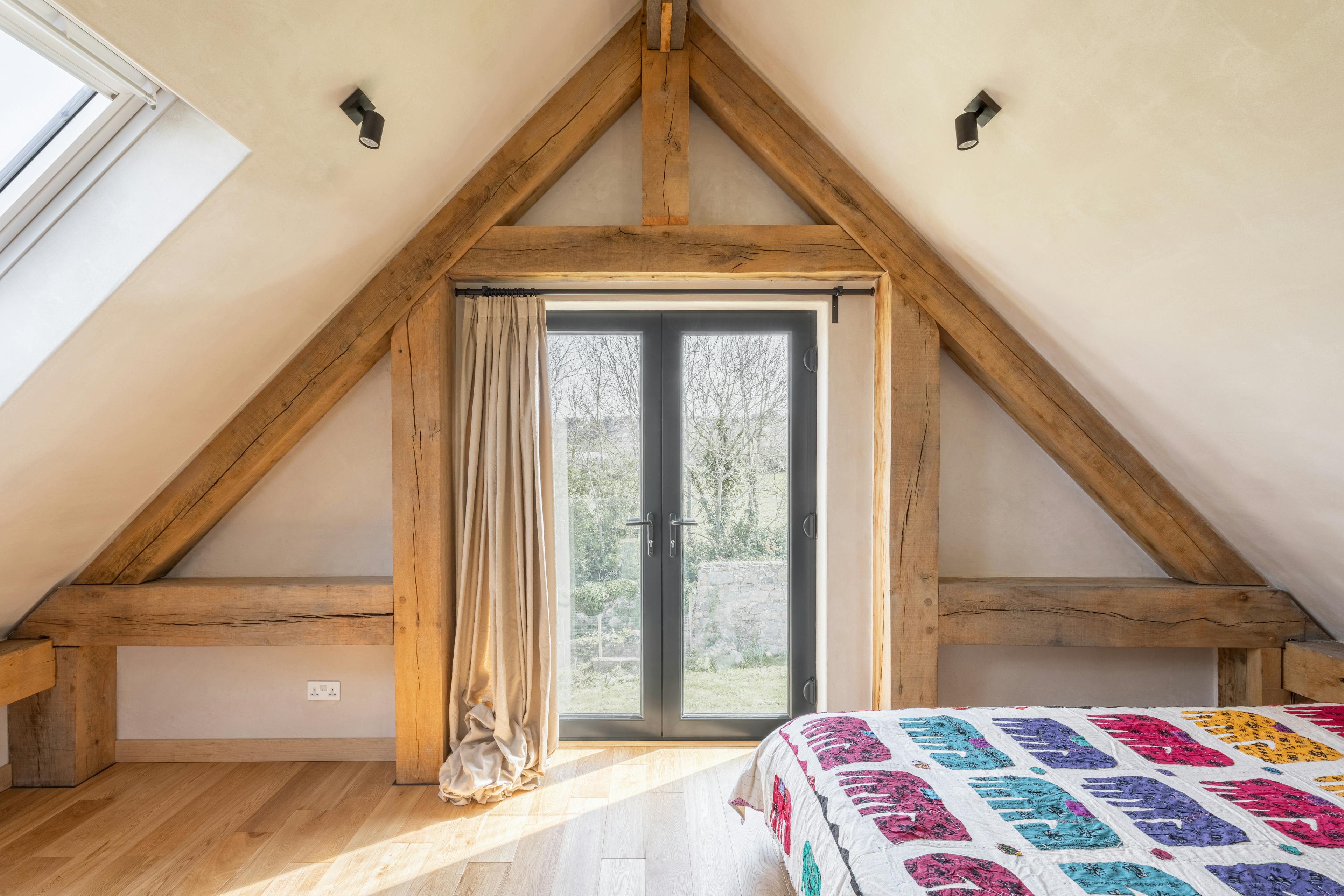 An oak framed bedroom in a roof space with sloping ceilings