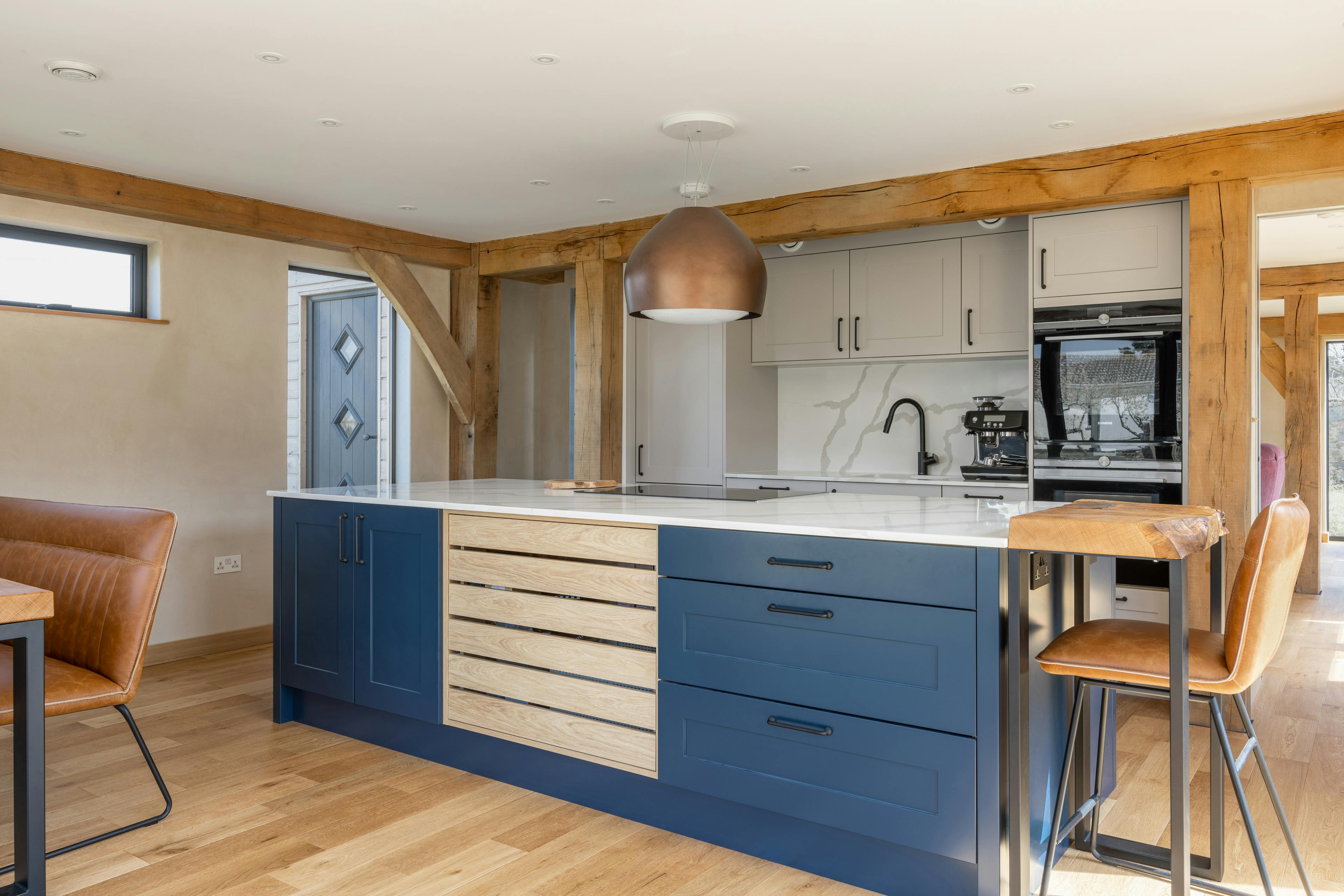 An oak framed kitchen with a blue painted island and wooden breakfast bar