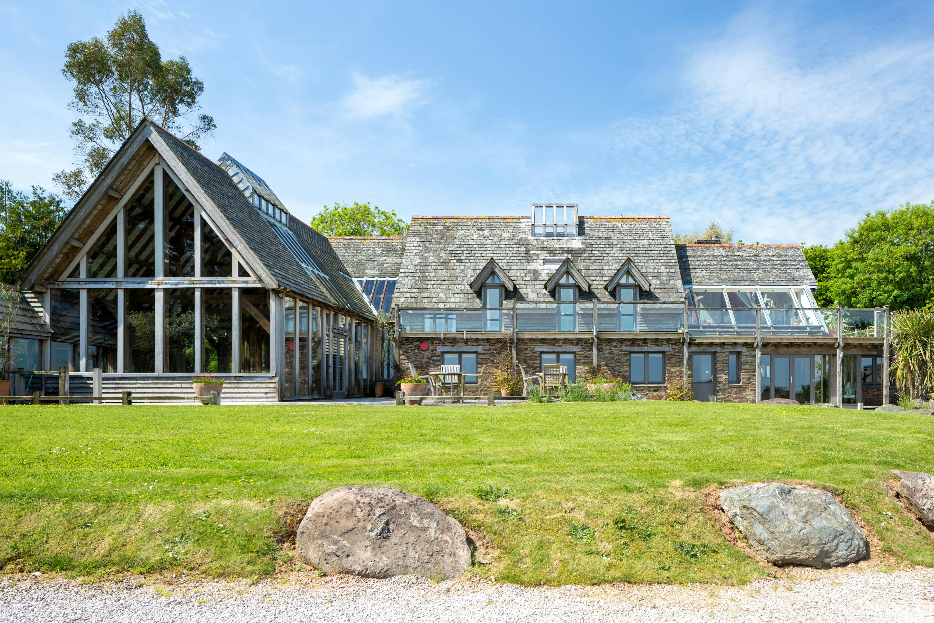 A large oak framed building with a green lawn in front