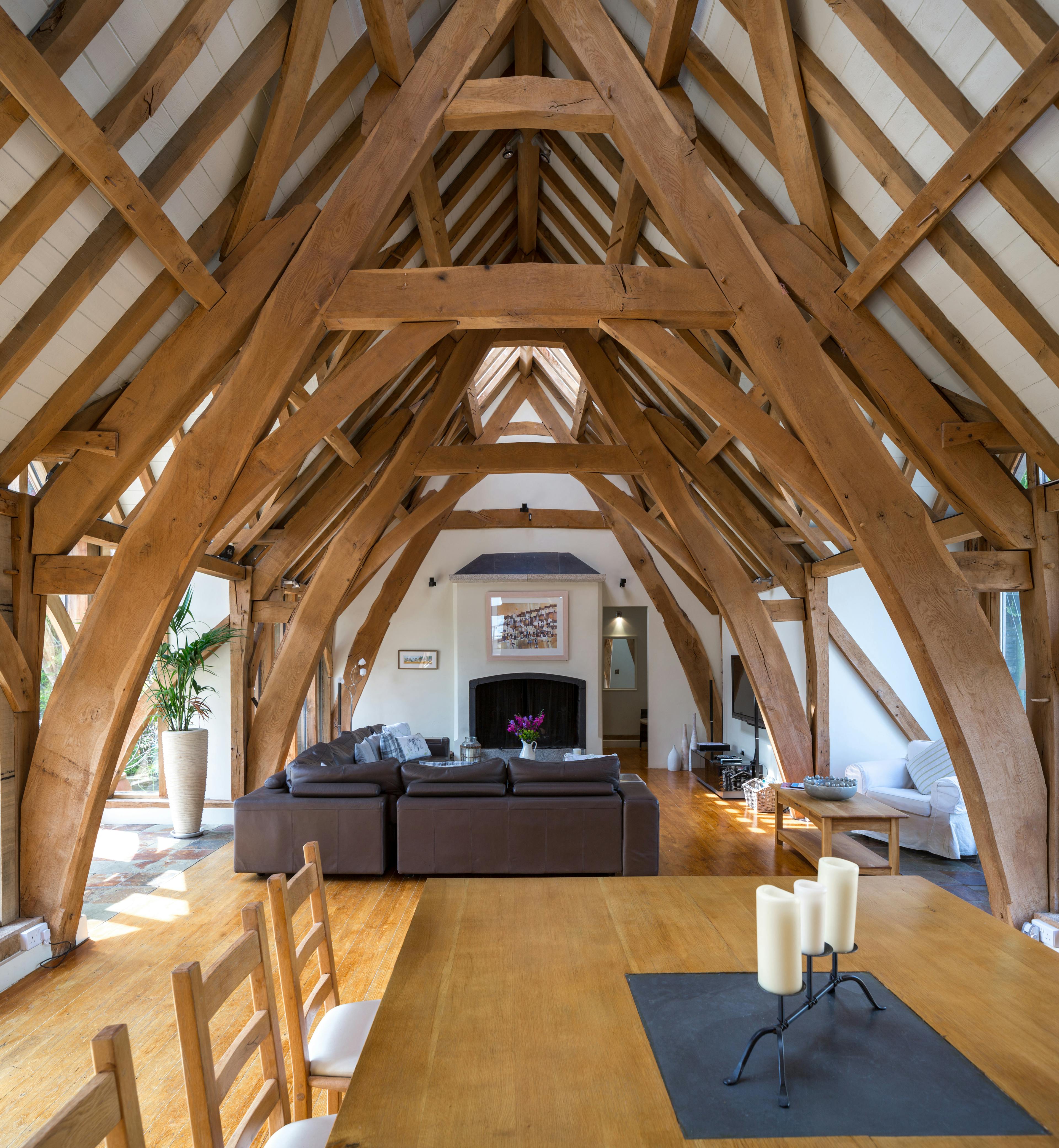 A large living sitting dining room with an oak frame cruck truss vaulted ceiling