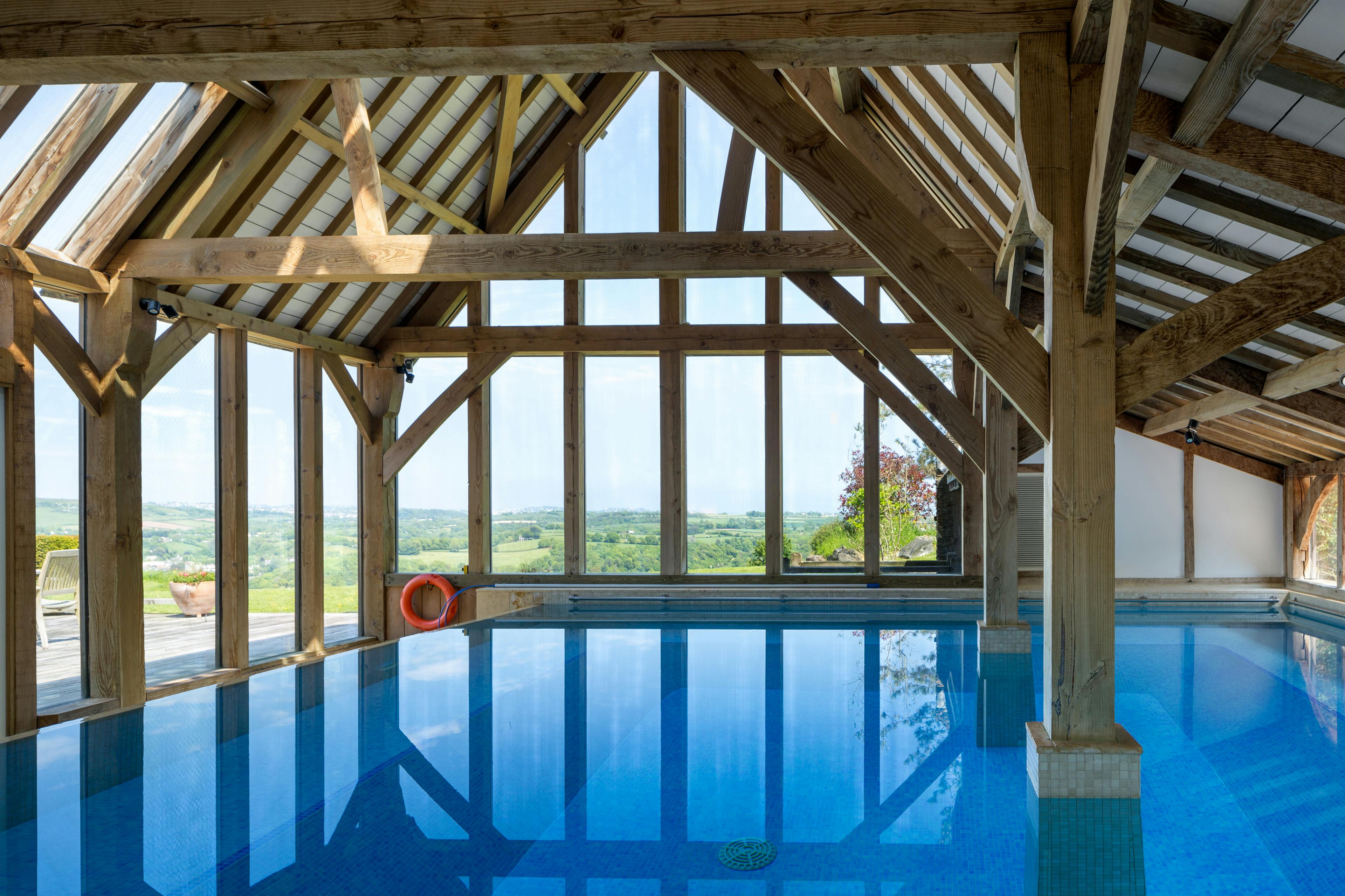 A large oak framed swimming pool building enclosure with glazed windows and views