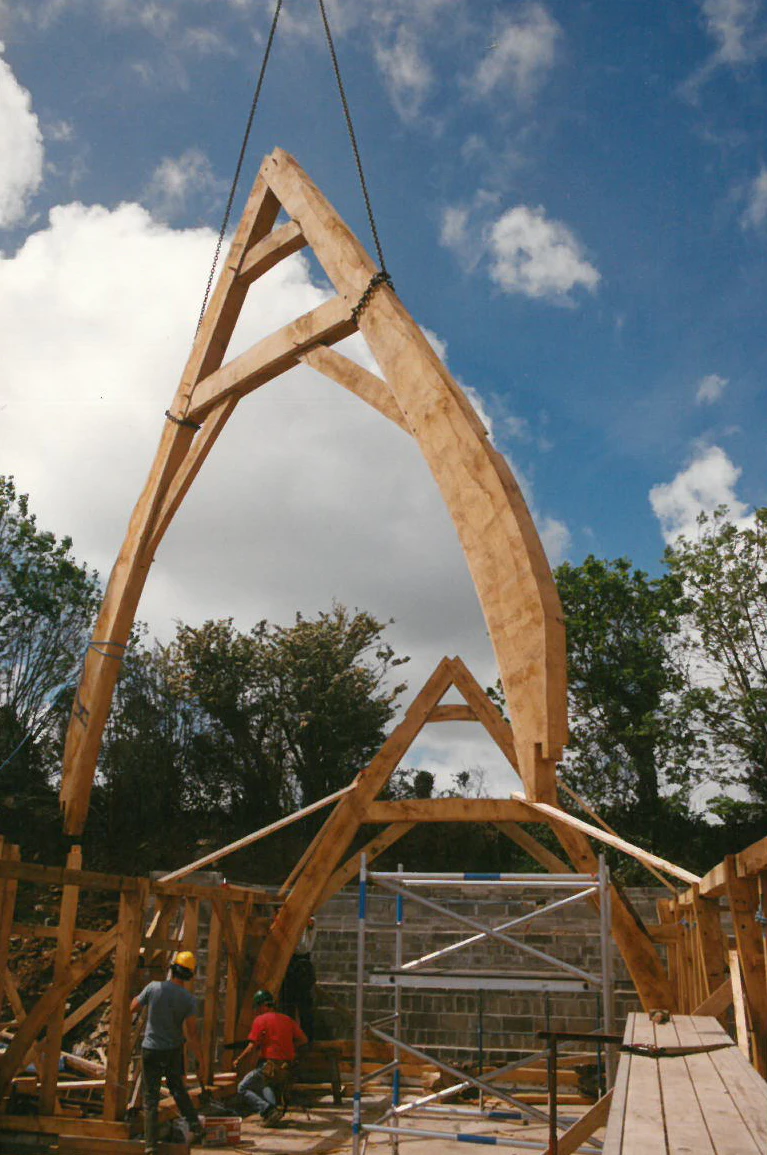An oak frame with a cruck truss during installation on a construction site