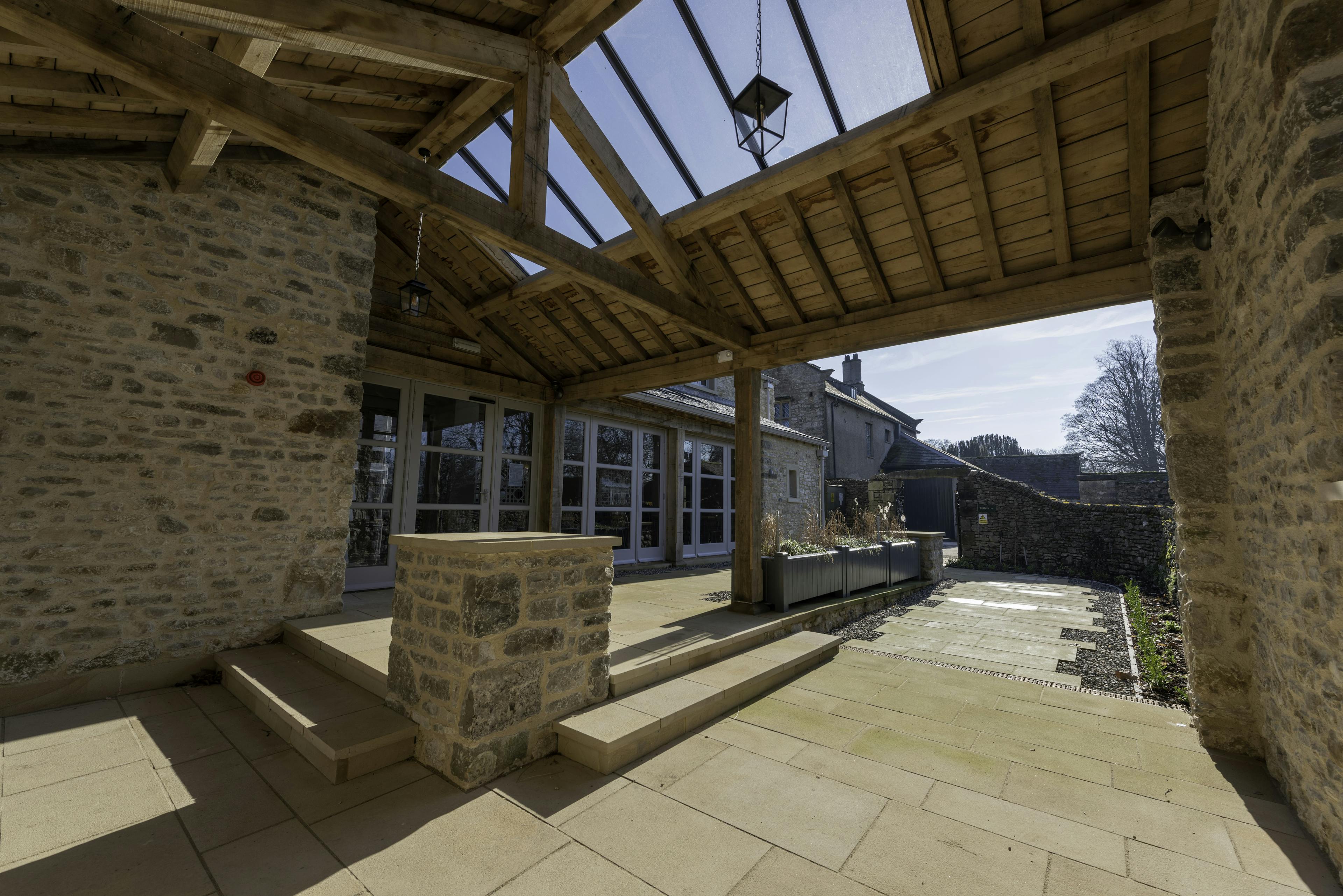An oak framed covered outdoor space with a brick wall