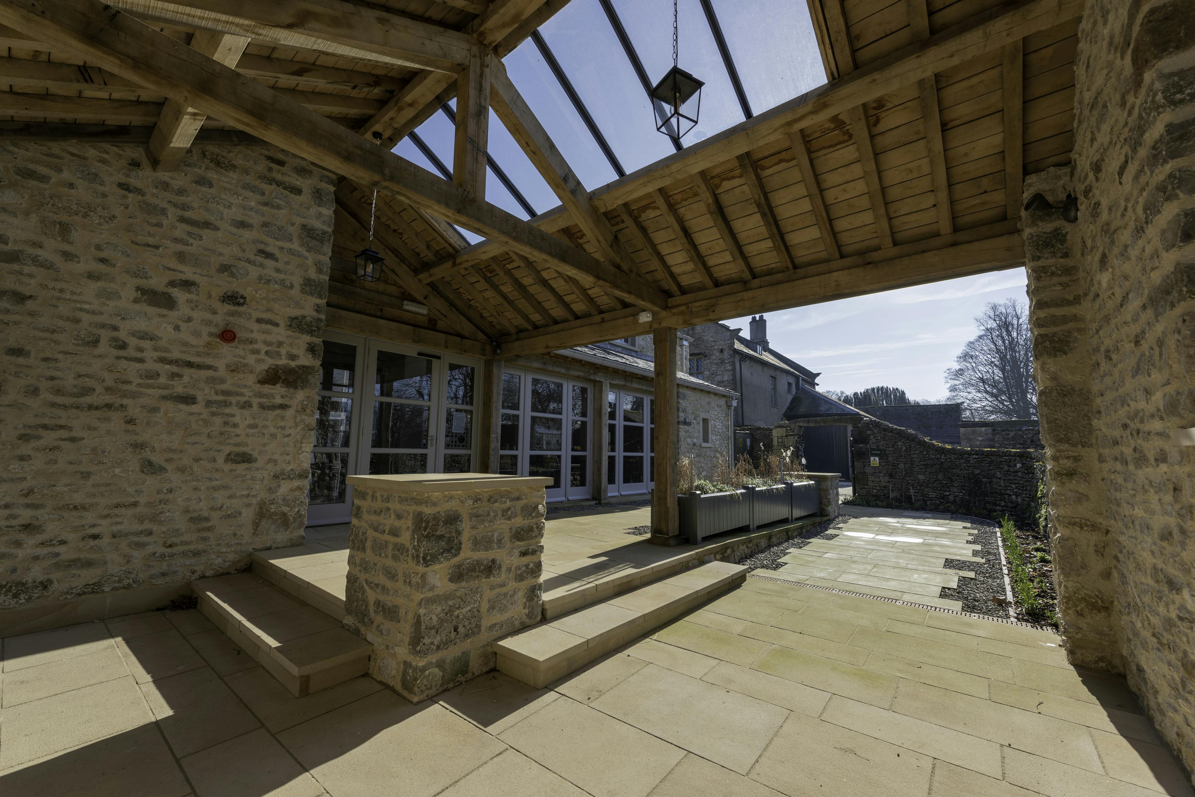 An oak framed covered outdoor space with a brick wall
