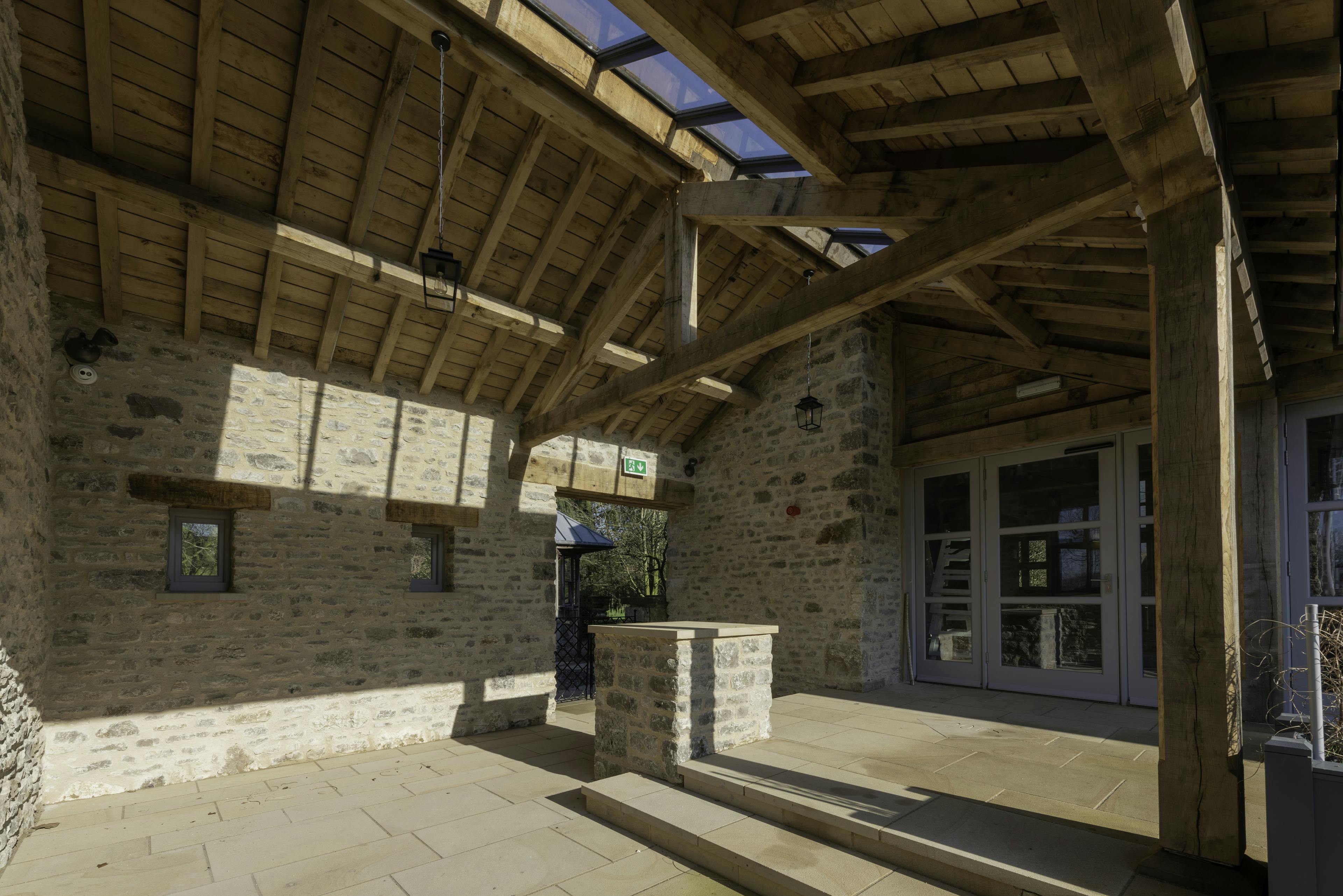 An oak framed covered outdoor space with a brick wall