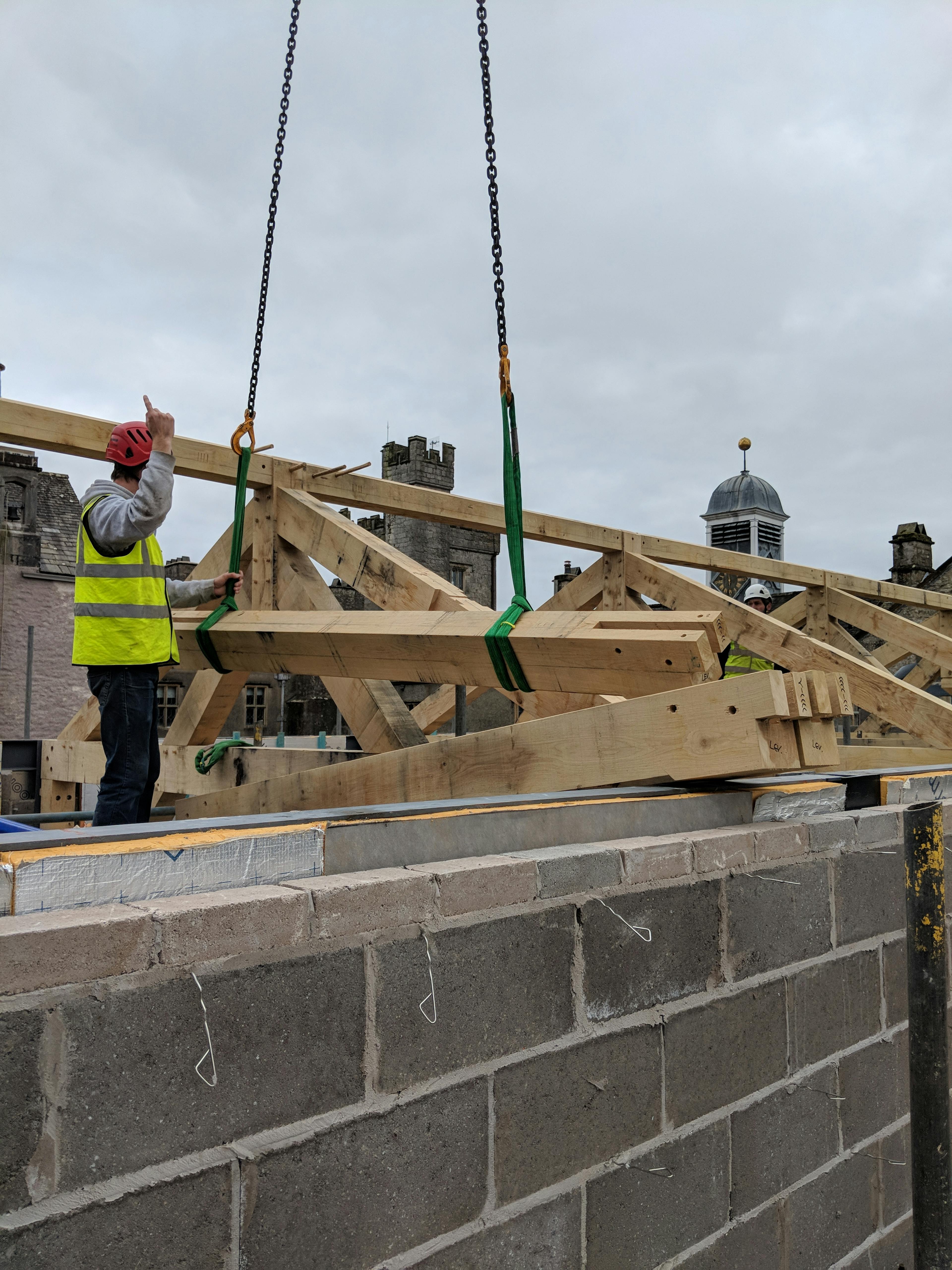 An oak frame is lowered into place by a crane during construction