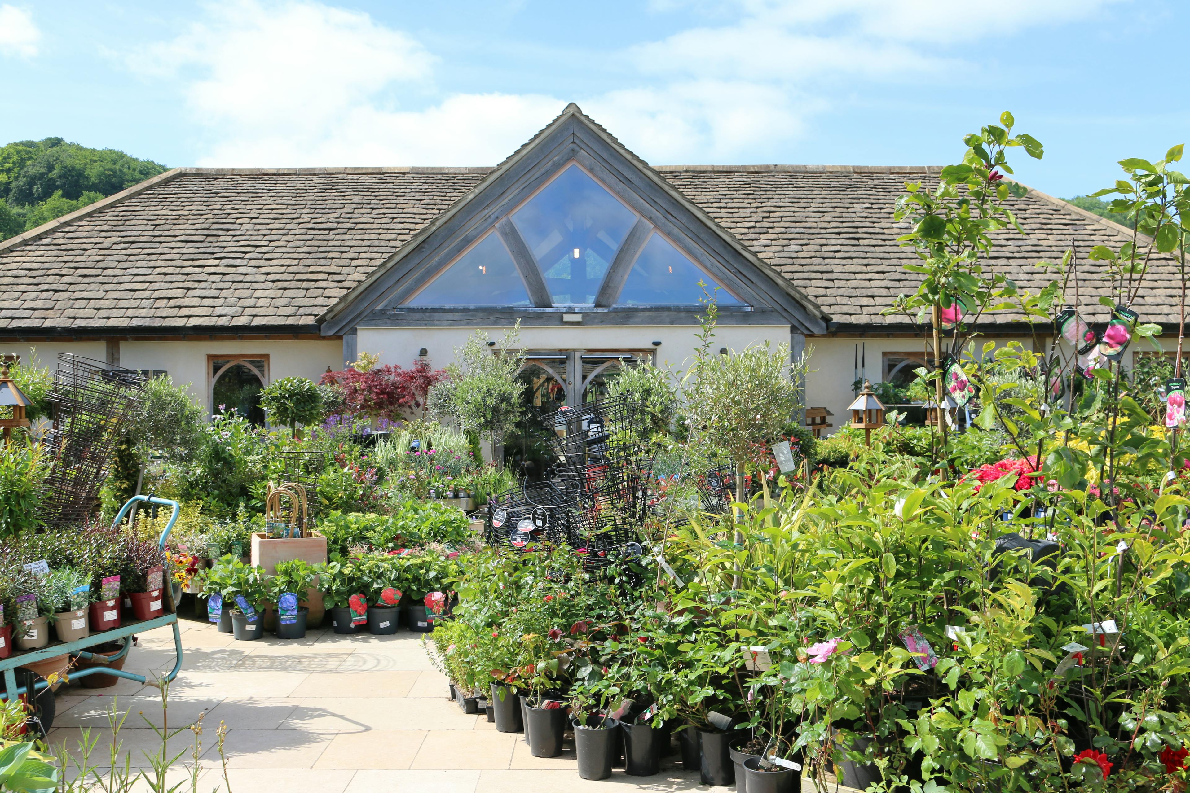 Oak framed garden centre with many plants and flowers on a courtyard in front