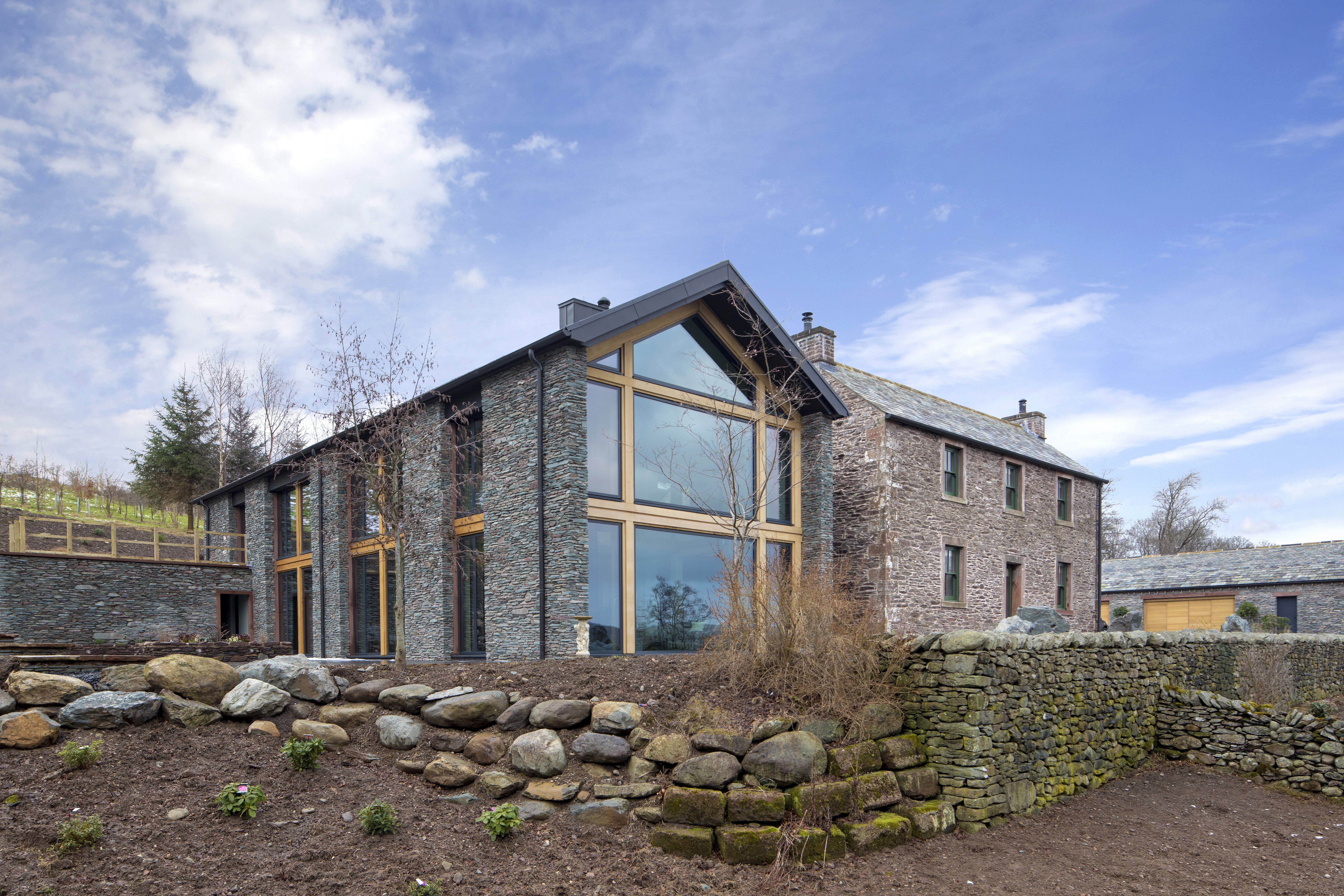 A large house with stone cladding and large wooden glazed windows