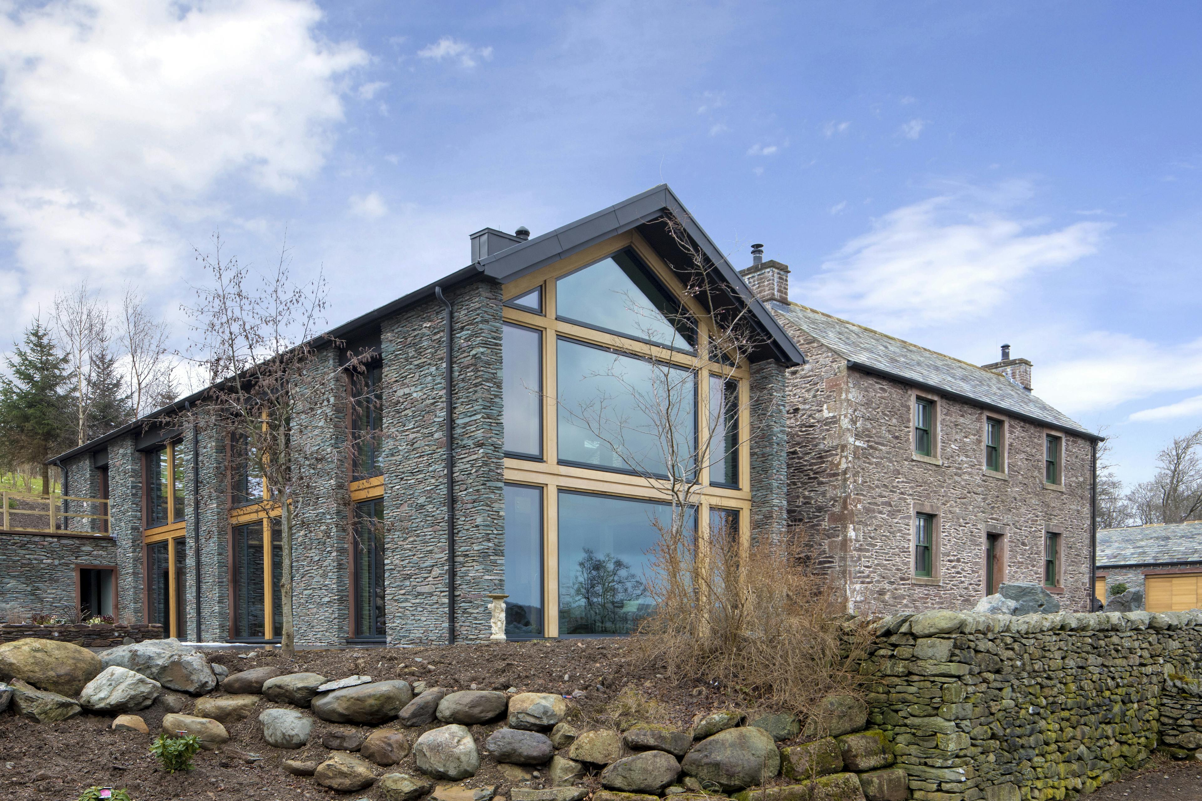 A large house with stone cladding and large wooden glazed windows