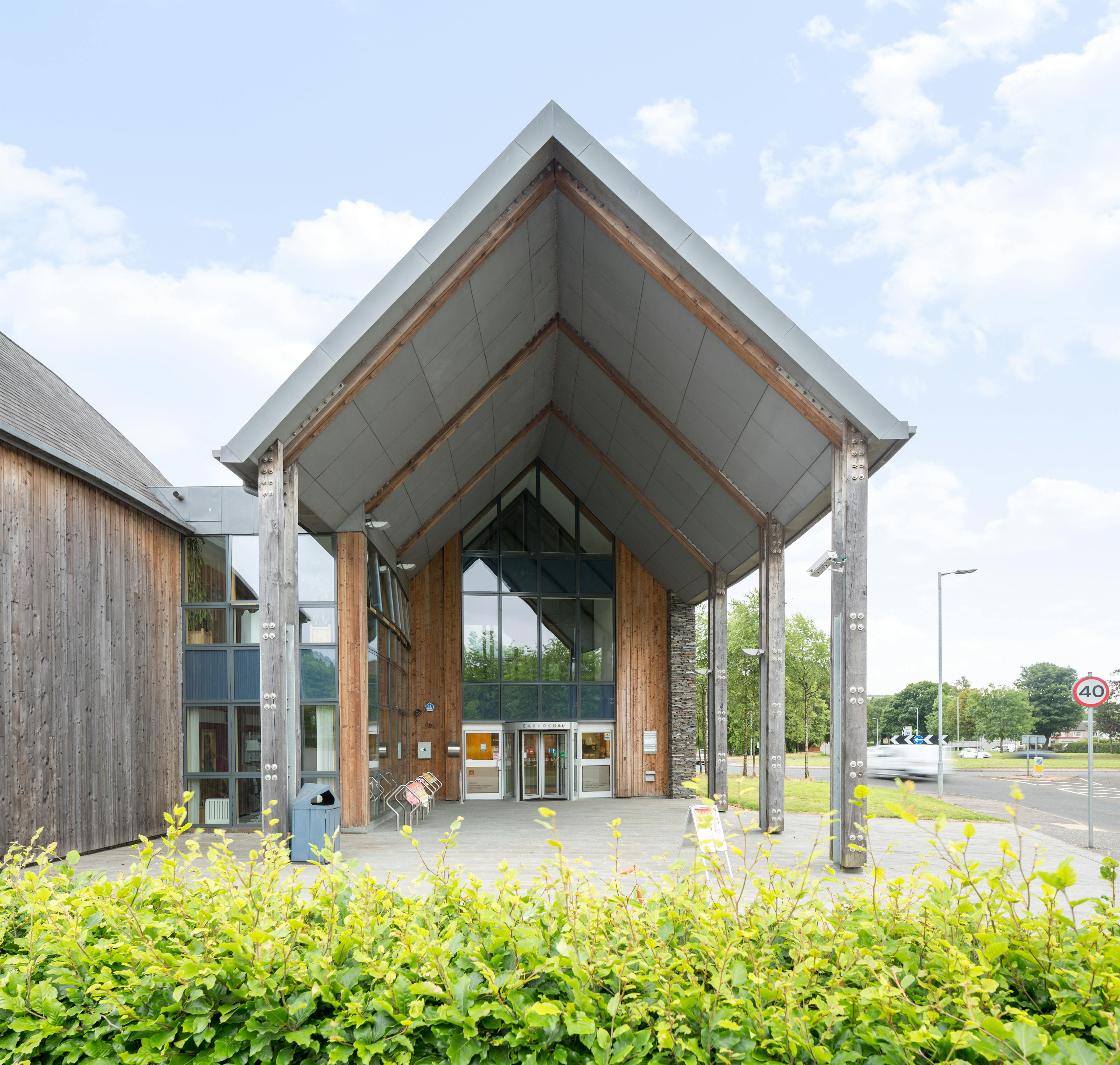 A timber clad large curved building with large glazed windows