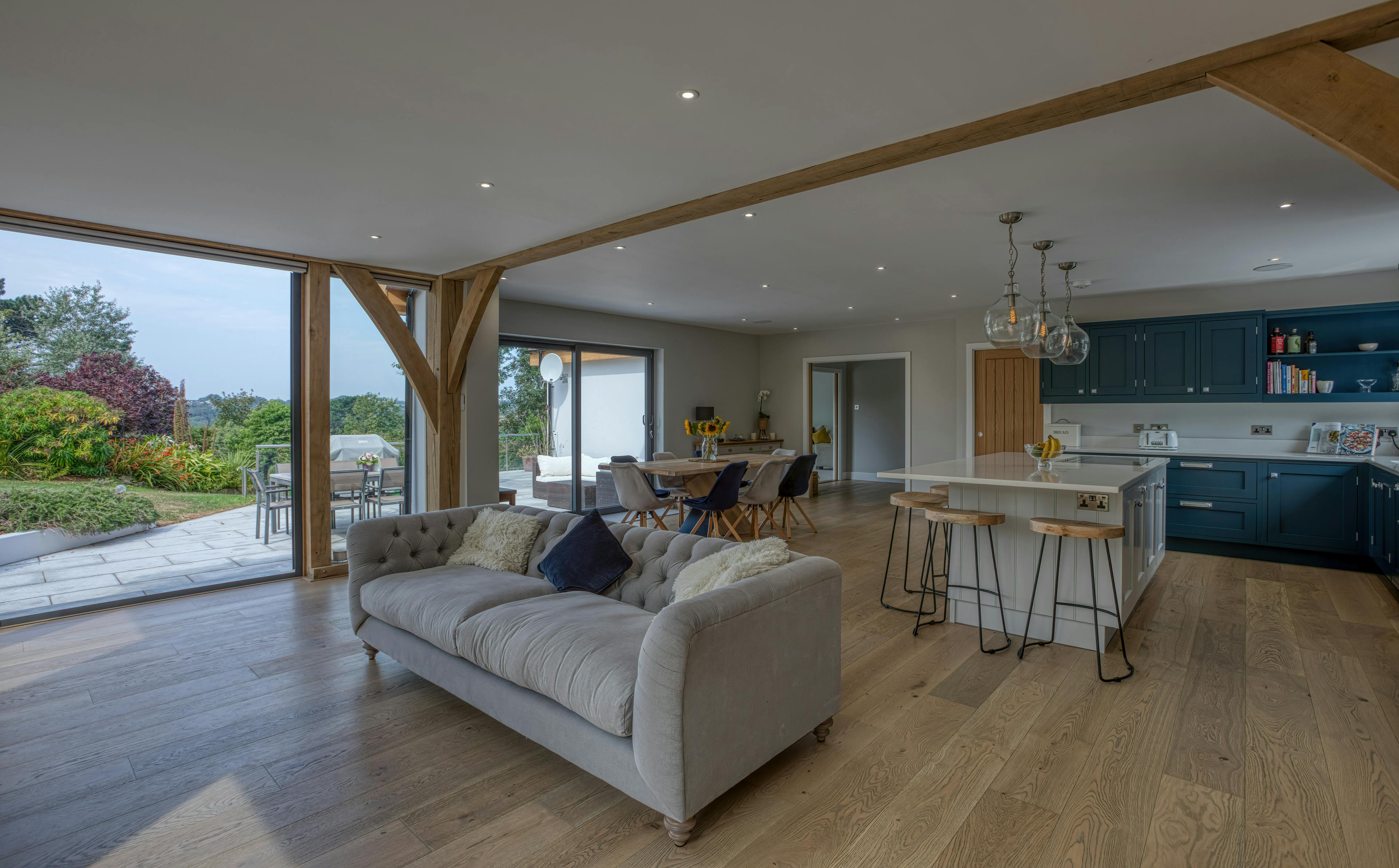 Interior view of an open-plan oak-framed extension with sitting, dining and kitchen areas