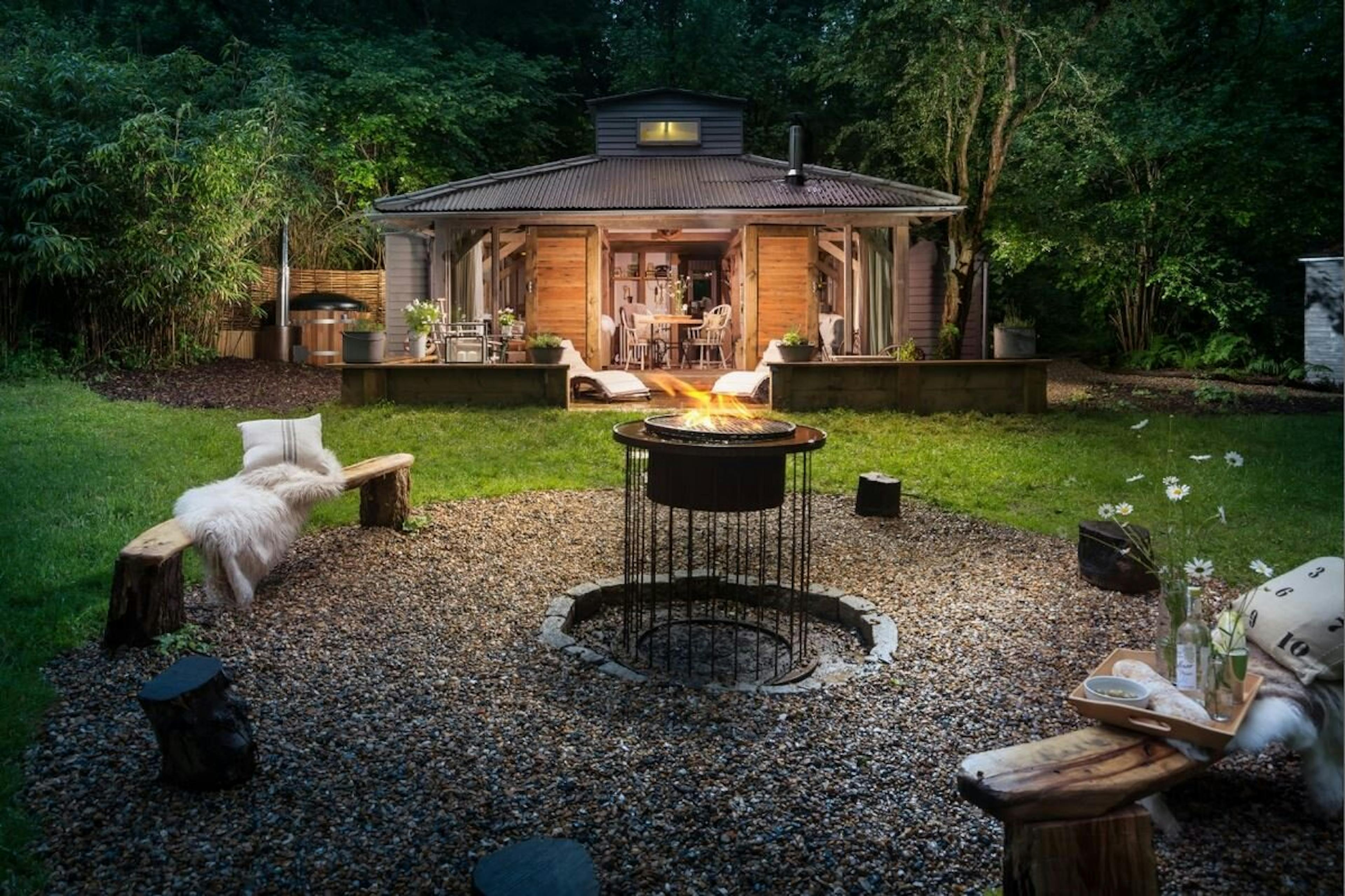 A fire pit in front of an oak framed cabin