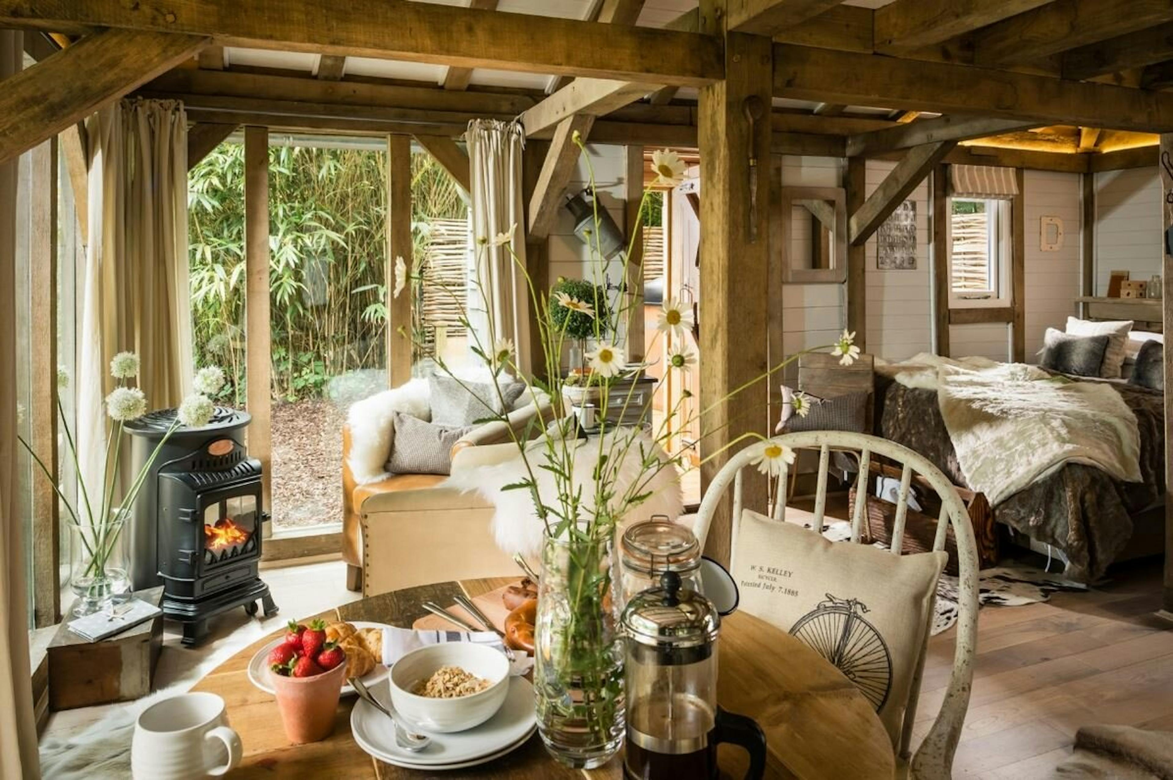 An open plan oak framed cabin with dining, bedroom areas and log burner