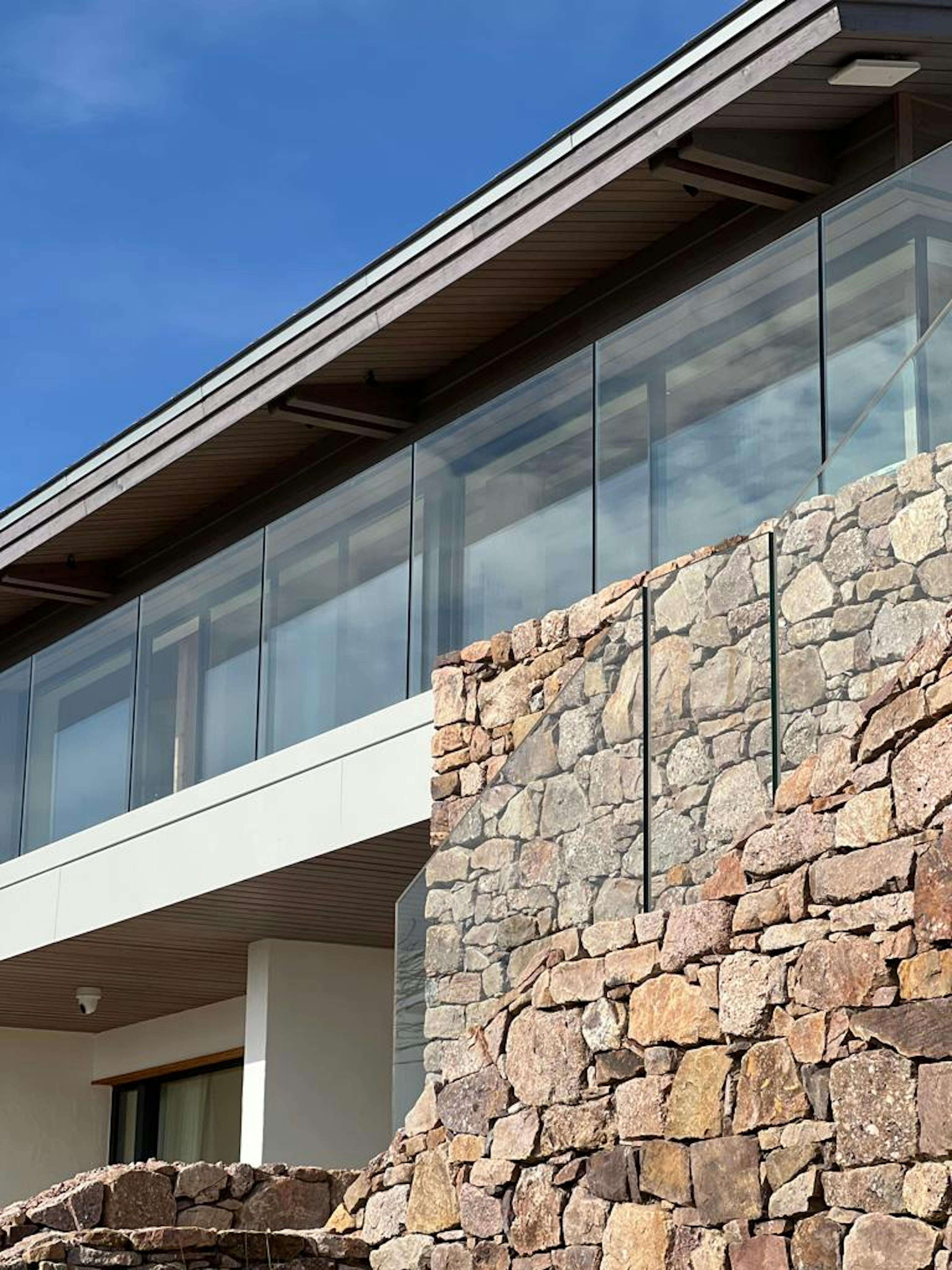 A new build home with stone cladding and a glazed balcony
