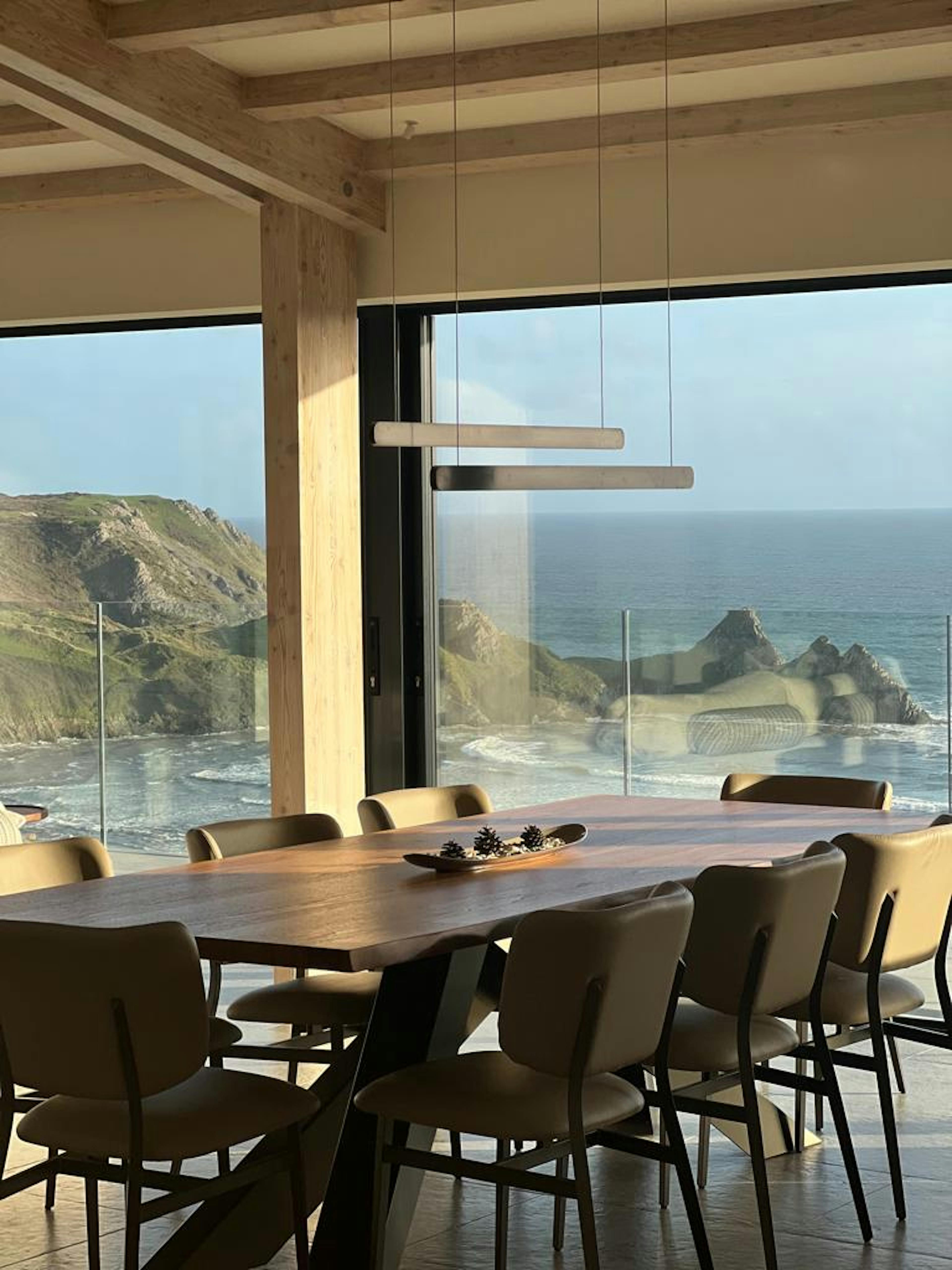 An oak glulam open plan living room with dining area and extensive glazing with views of the sea