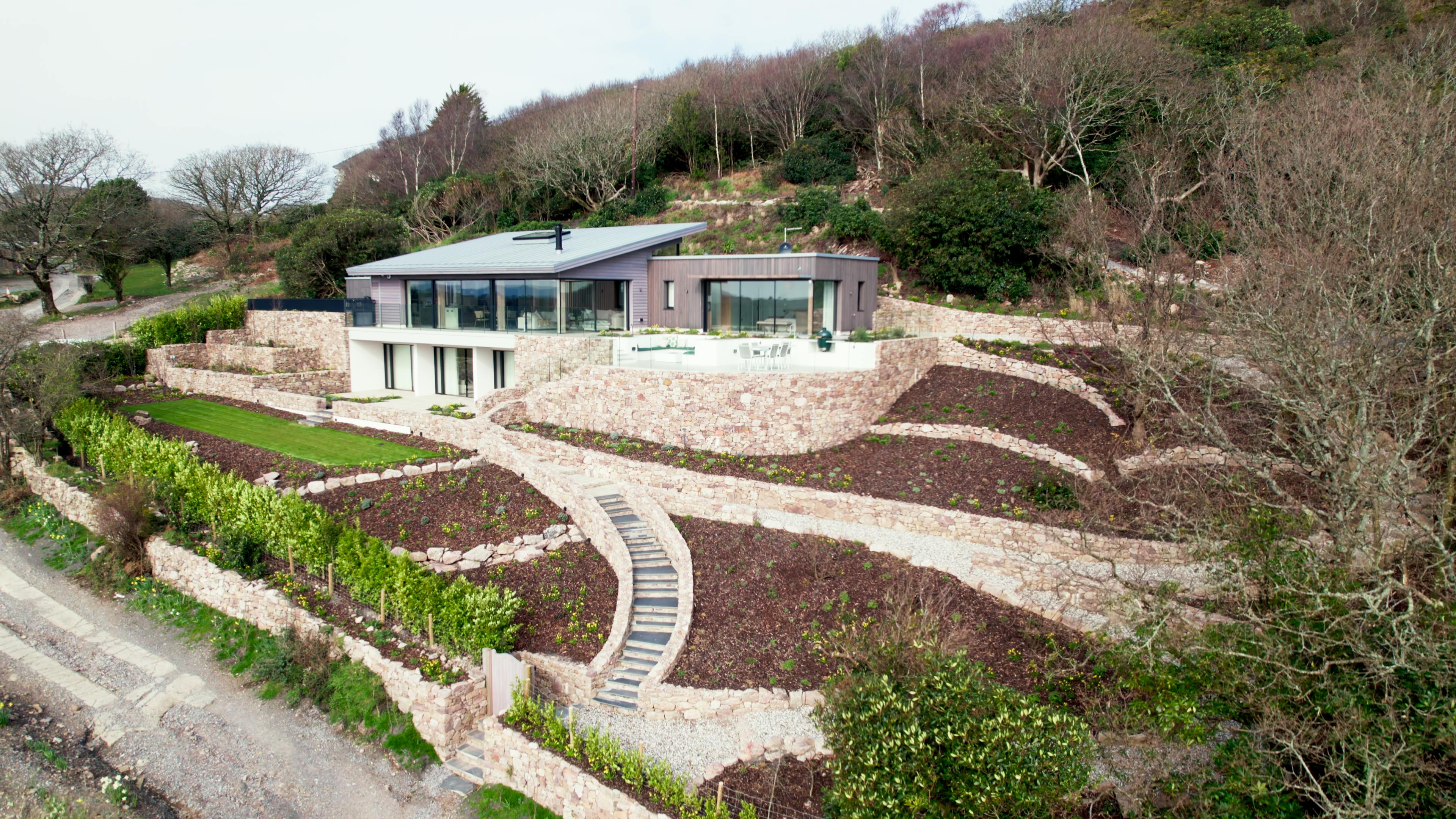 A timber clad new build home with dry stone walling in the landscaped garden