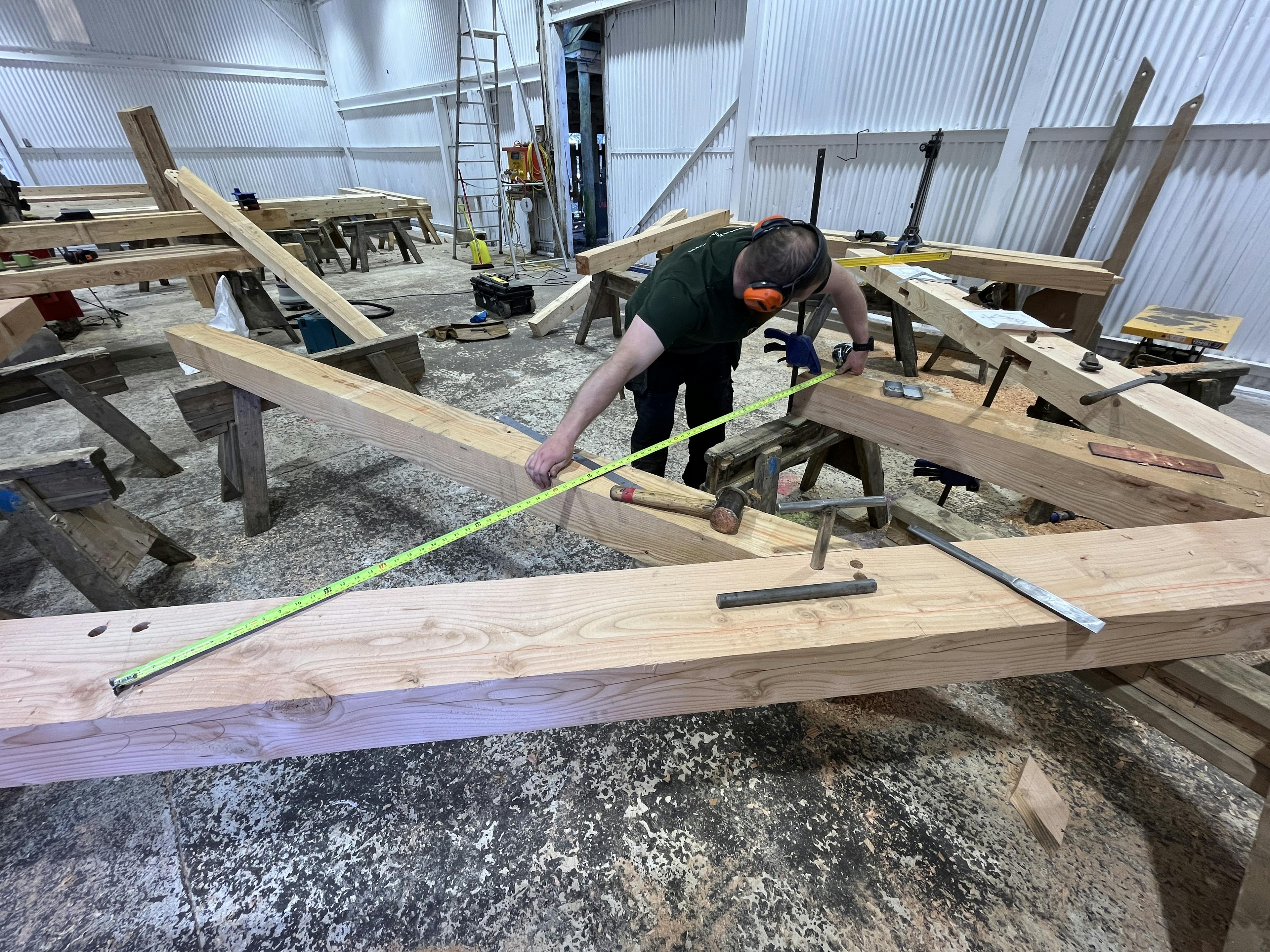 A carpenter handcrafting the larch frame for a timber structured outdoor classroom