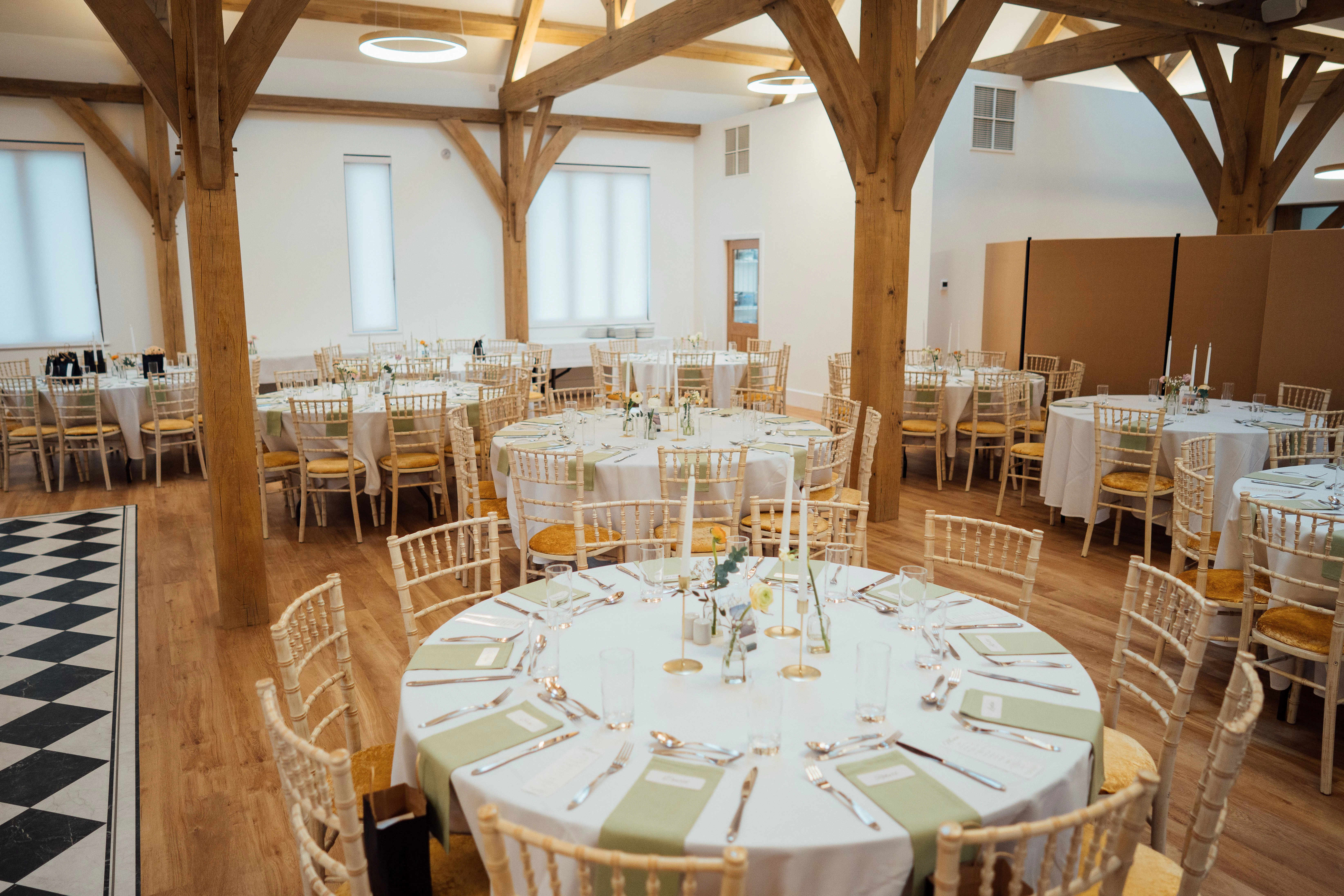 An oak framed wedding barn with tables and chairs set up ready for guests