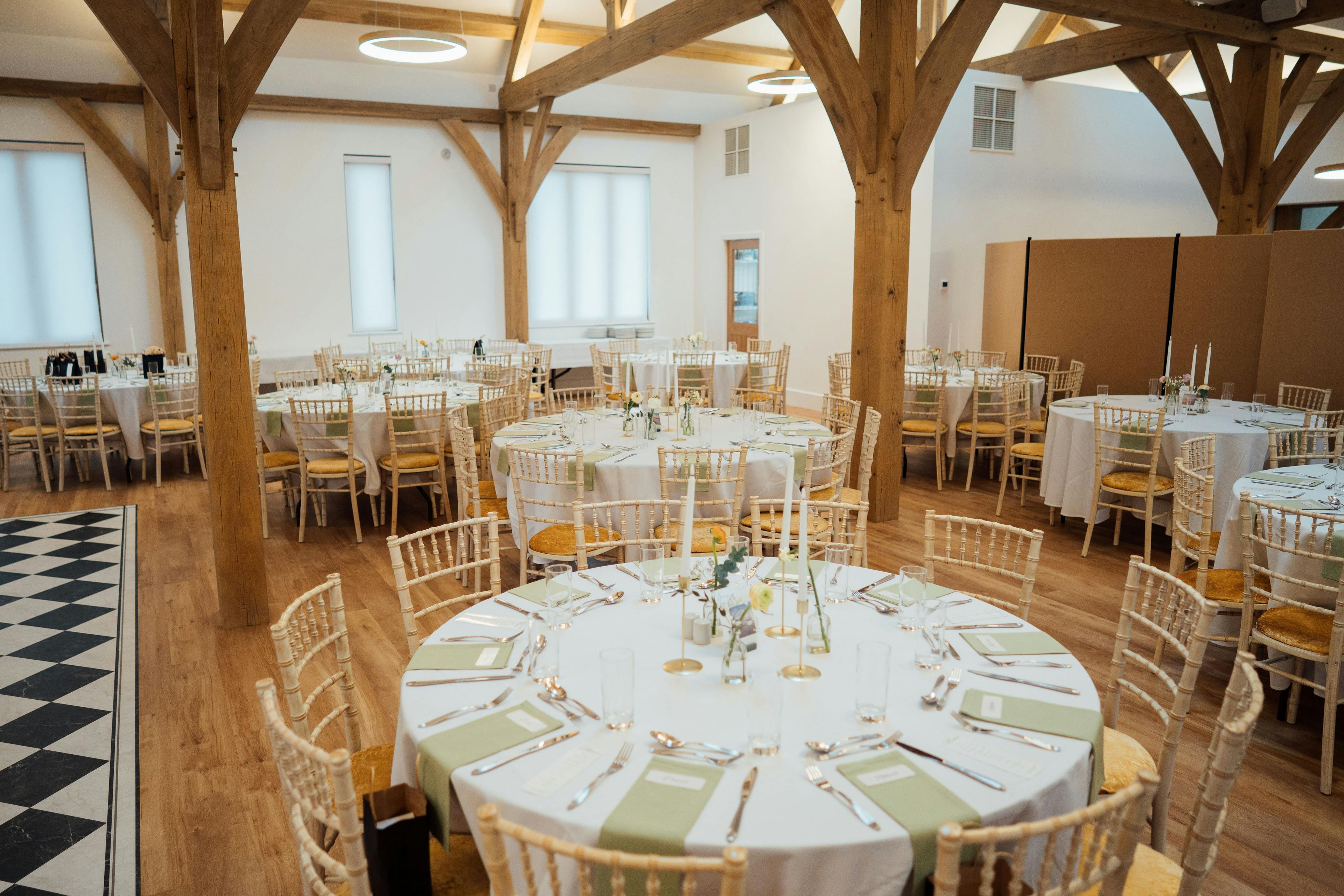 An oak framed wedding barn with tables and chairs set up ready for guests