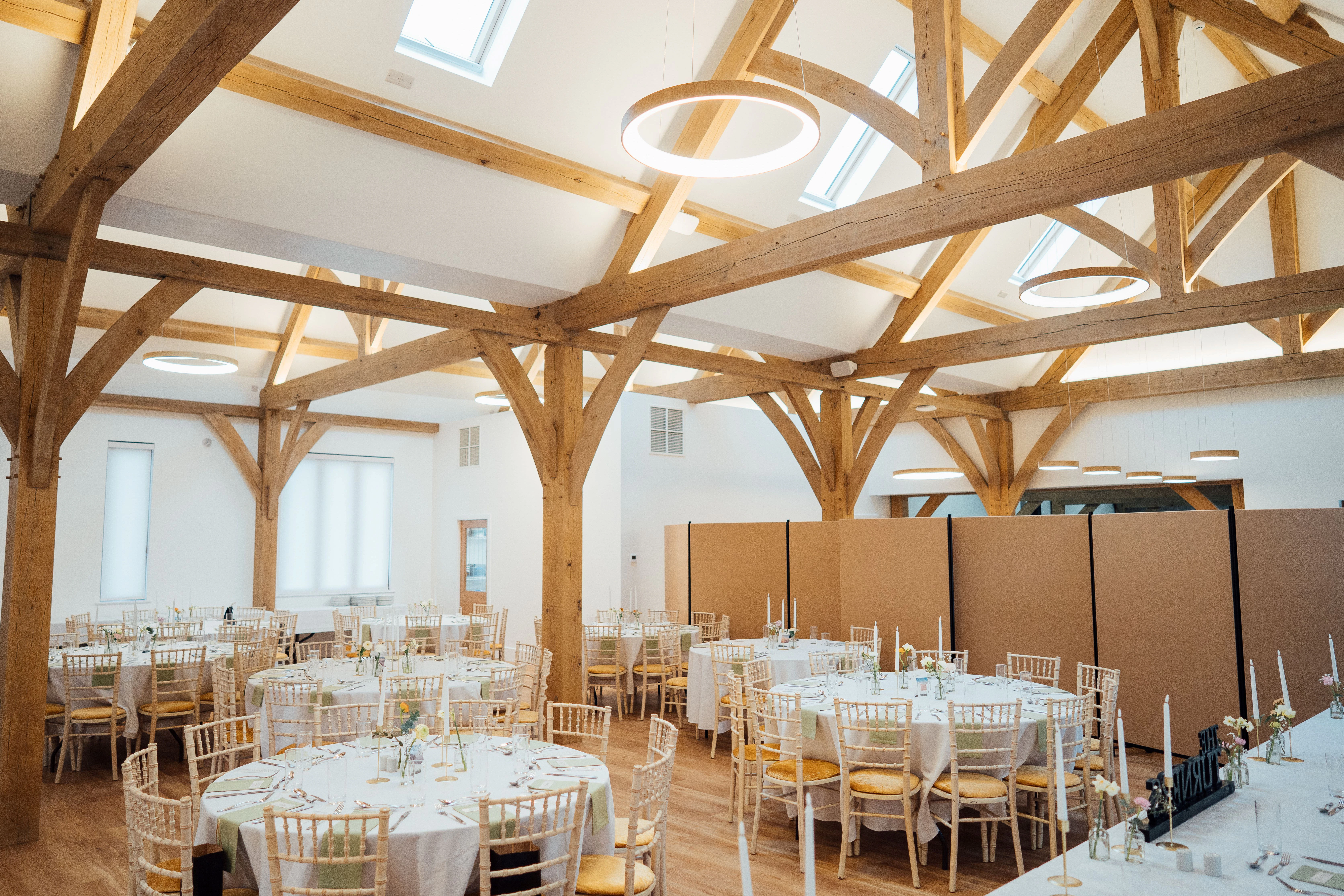 An oak framed wedding barn with tables and chairs set up ready for guests