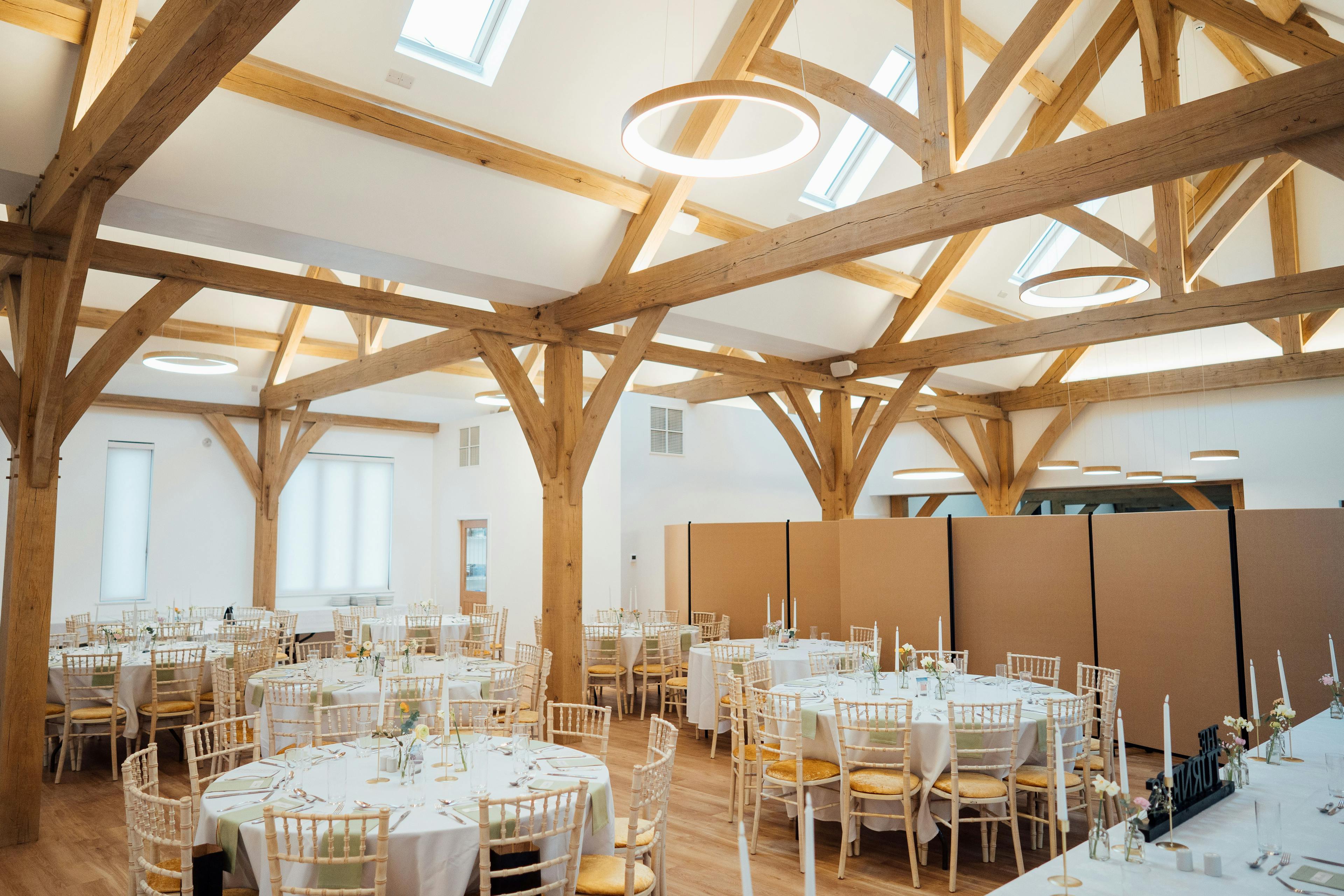 An oak framed wedding barn with tables and chairs set up ready for guests