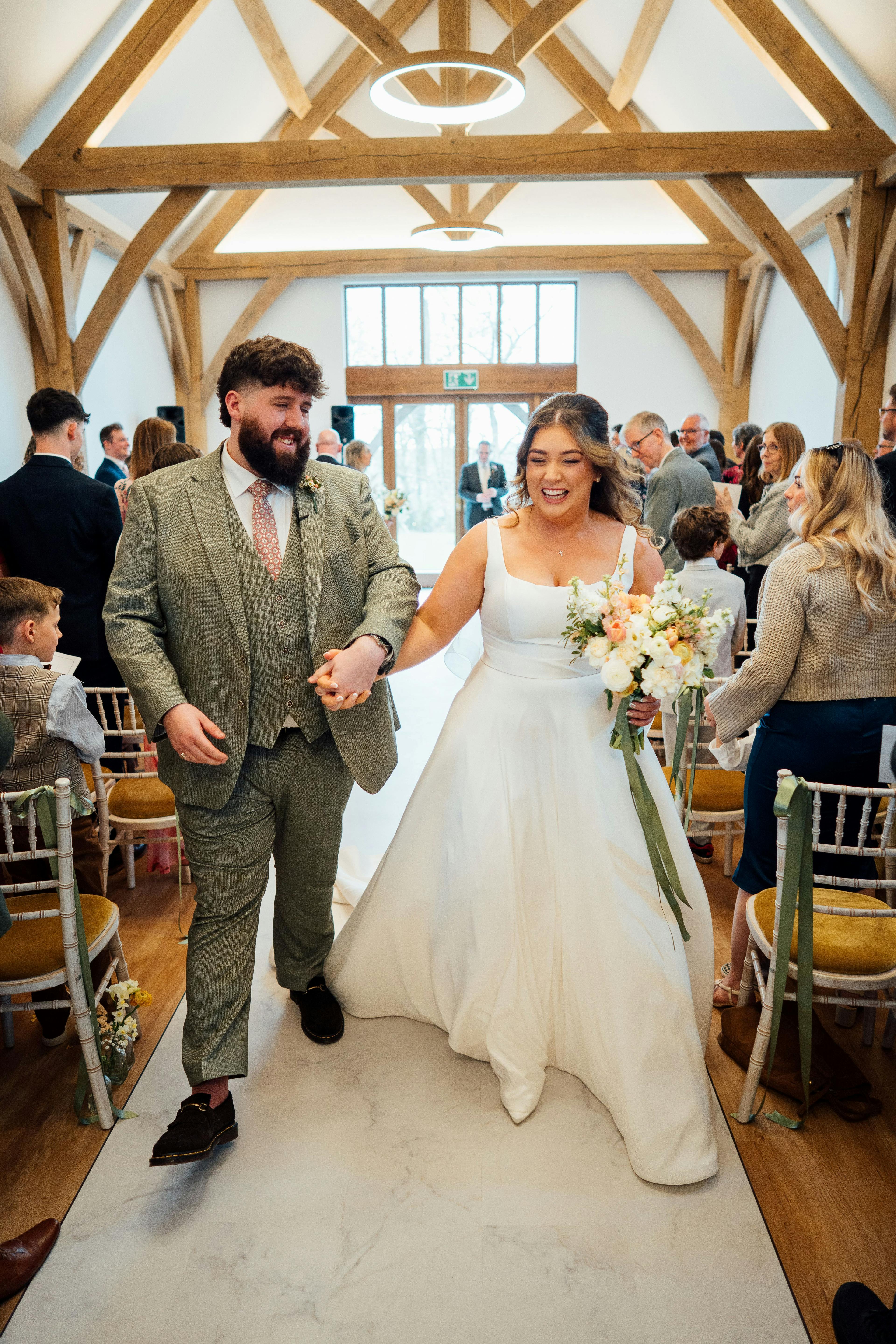A bride and groom and guests in the ceremony room in an oak framed wedding barn 