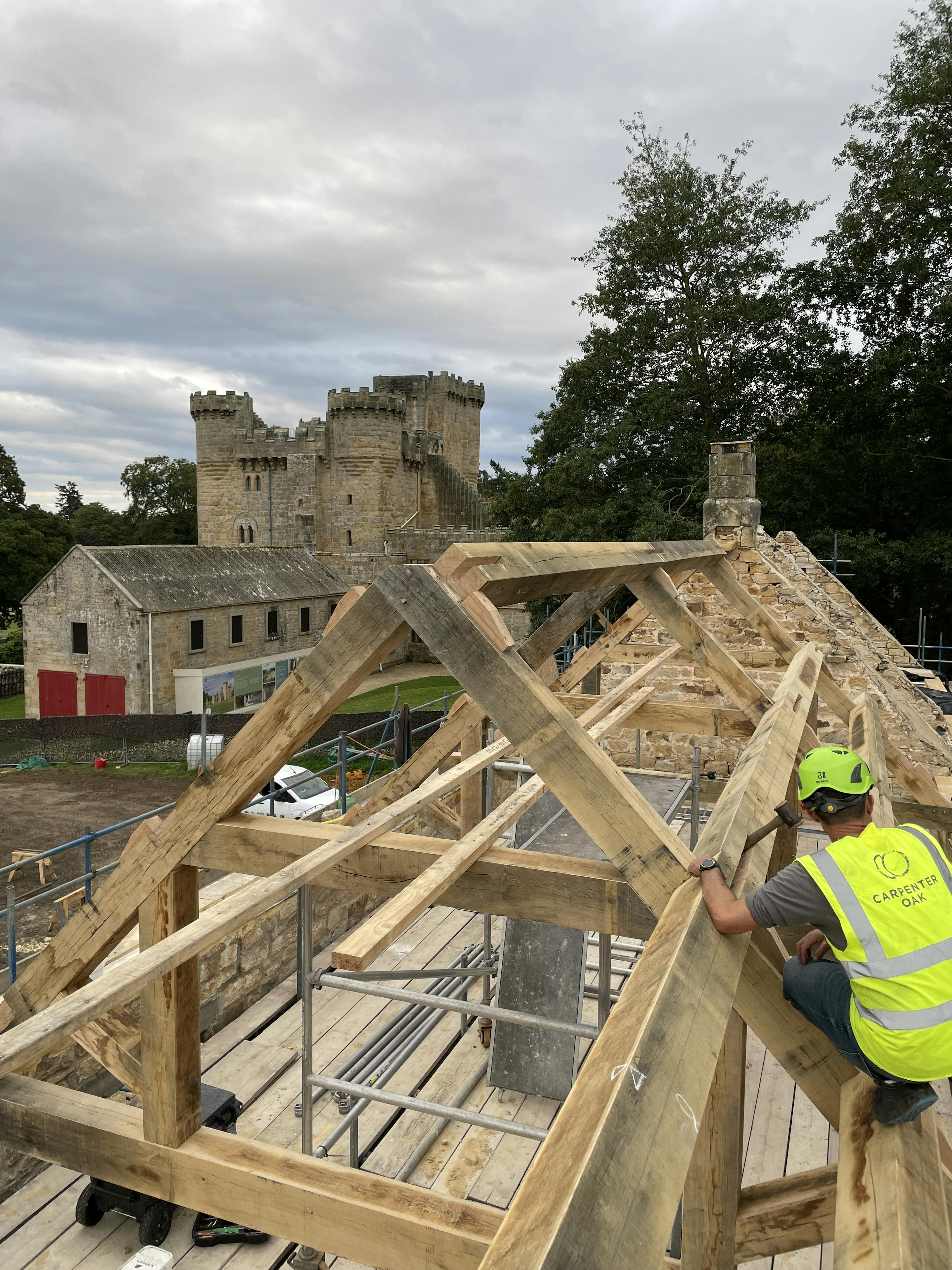 A carpenter installs oak trusses for a renovated coach house to create a new cafe for visitors to Belsay Hall