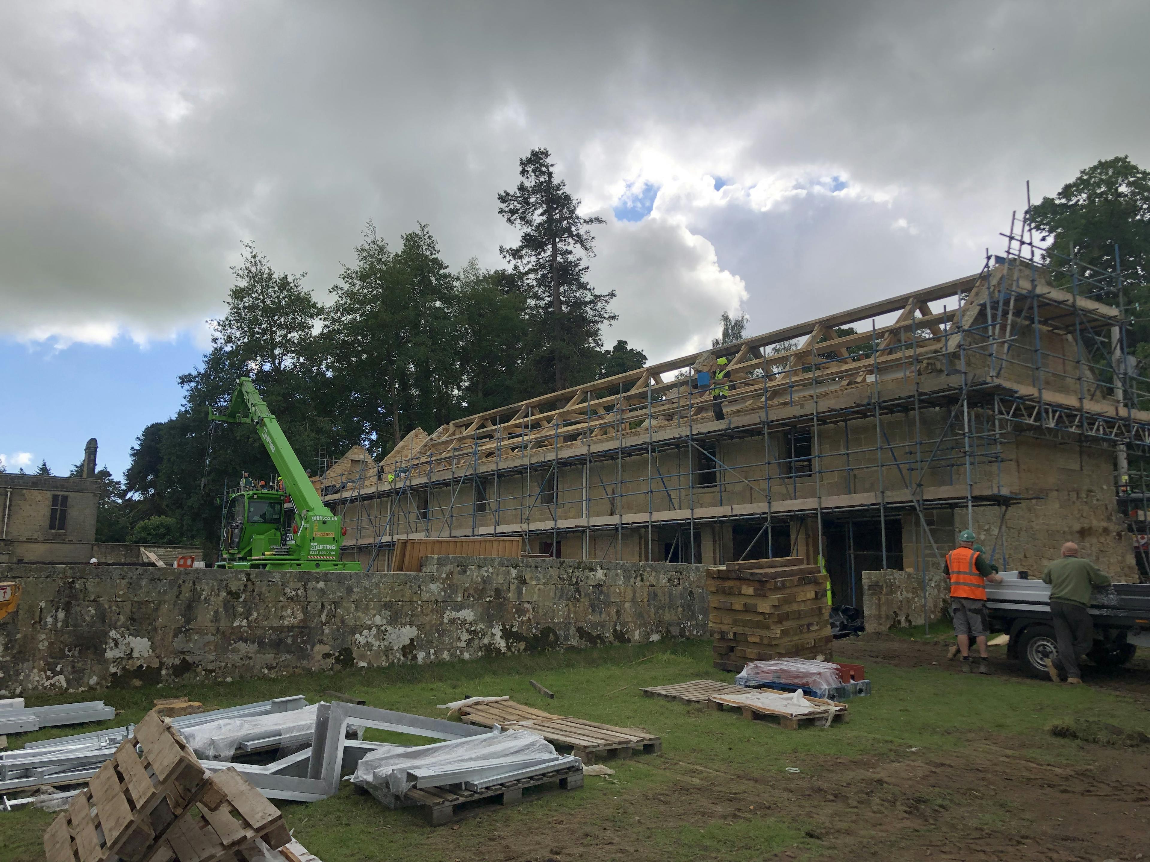 Oak trusses being installed in a renovated coach house to create a new cafe for visitors to Belsay Hall