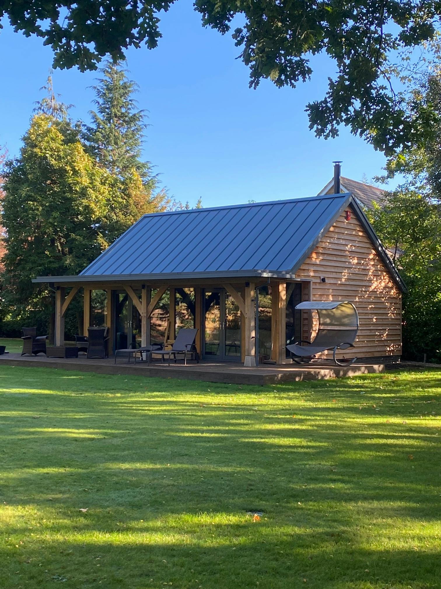 A green lawn in front of an oak framed annexe summer house