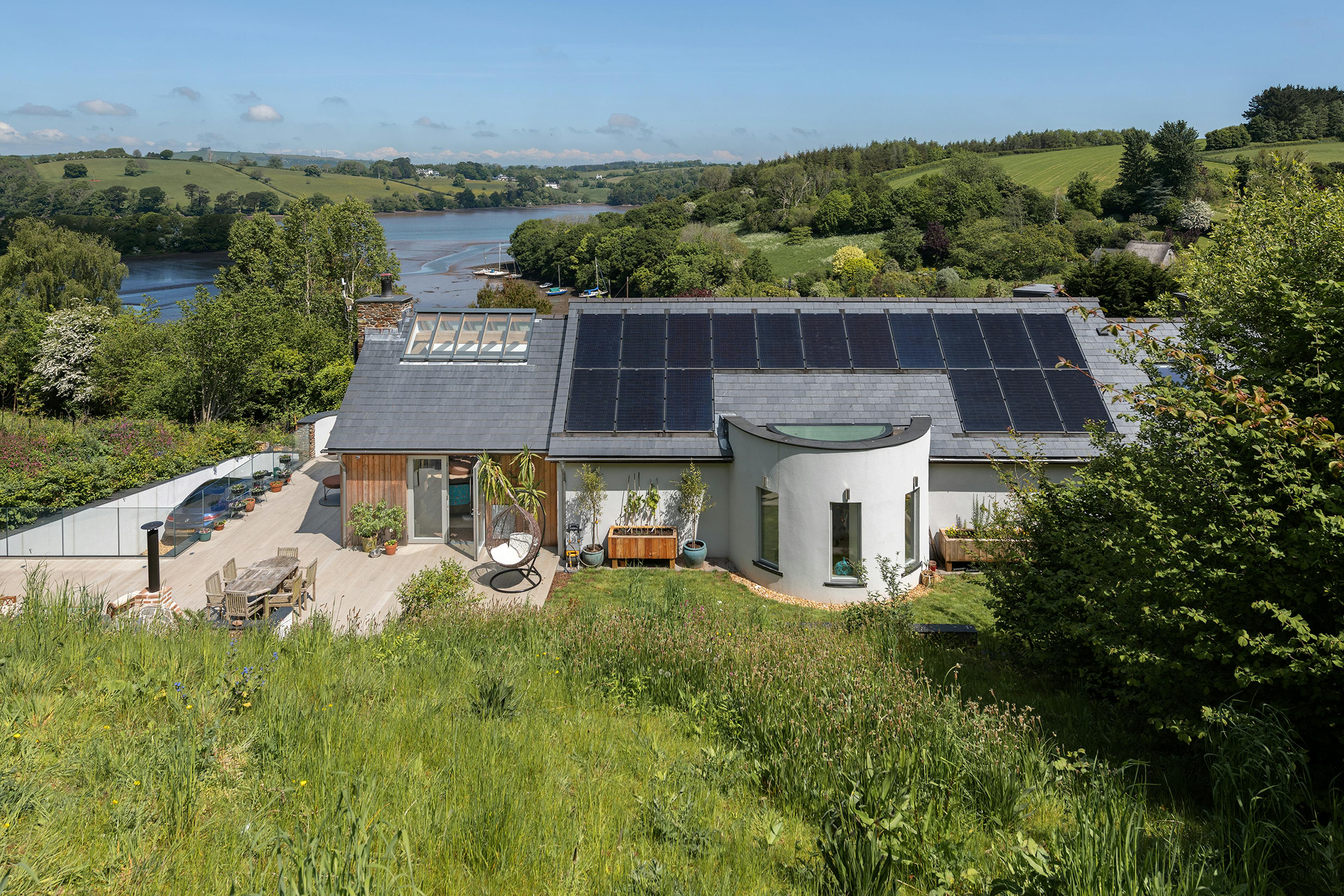 The rear view of an oak framed reverse level home with views of an estuary and solar panels on the roof.