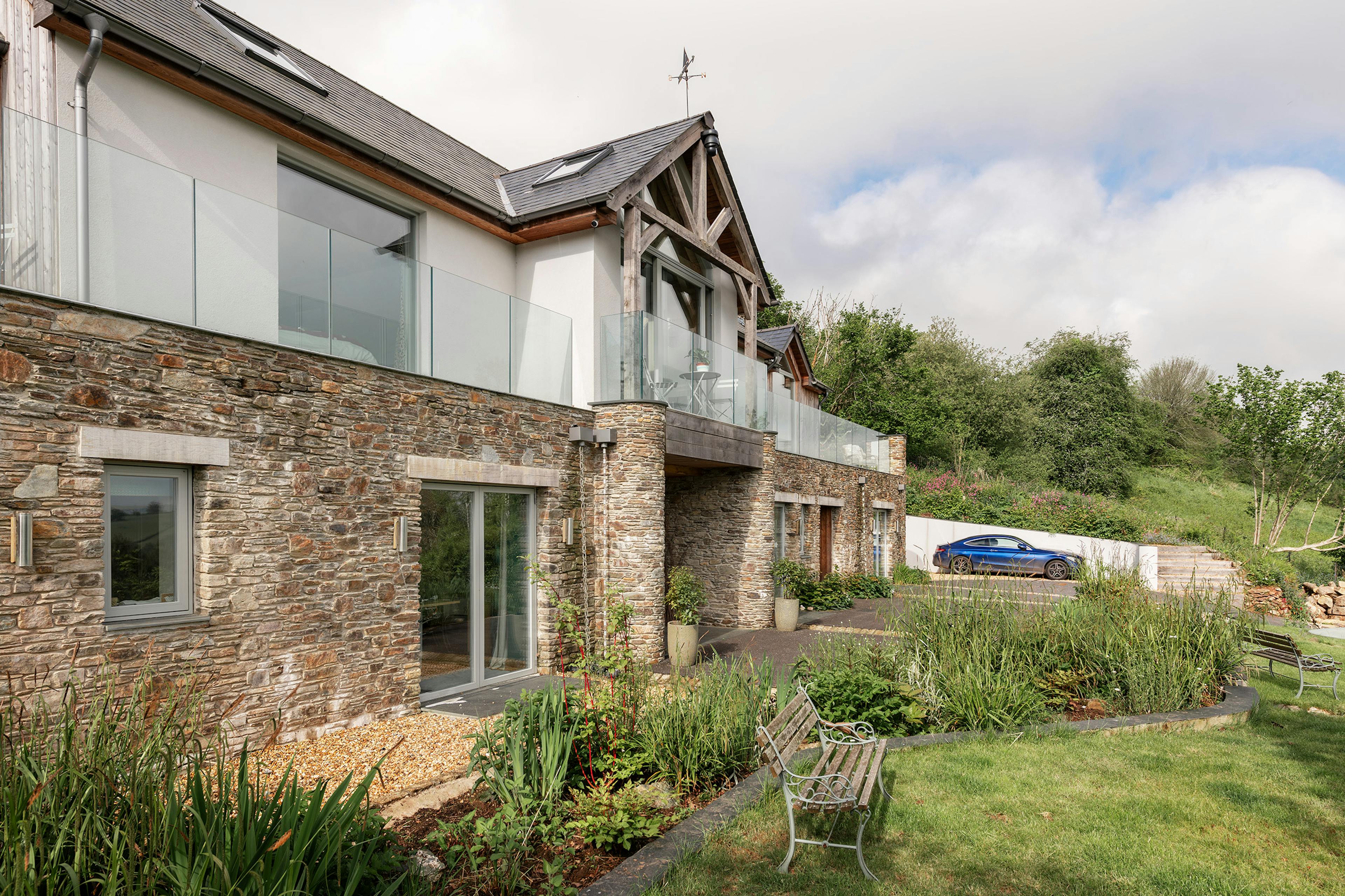 The front view of an oak framed reverse level home with an oak framed balcony and stone cladding on the lower level