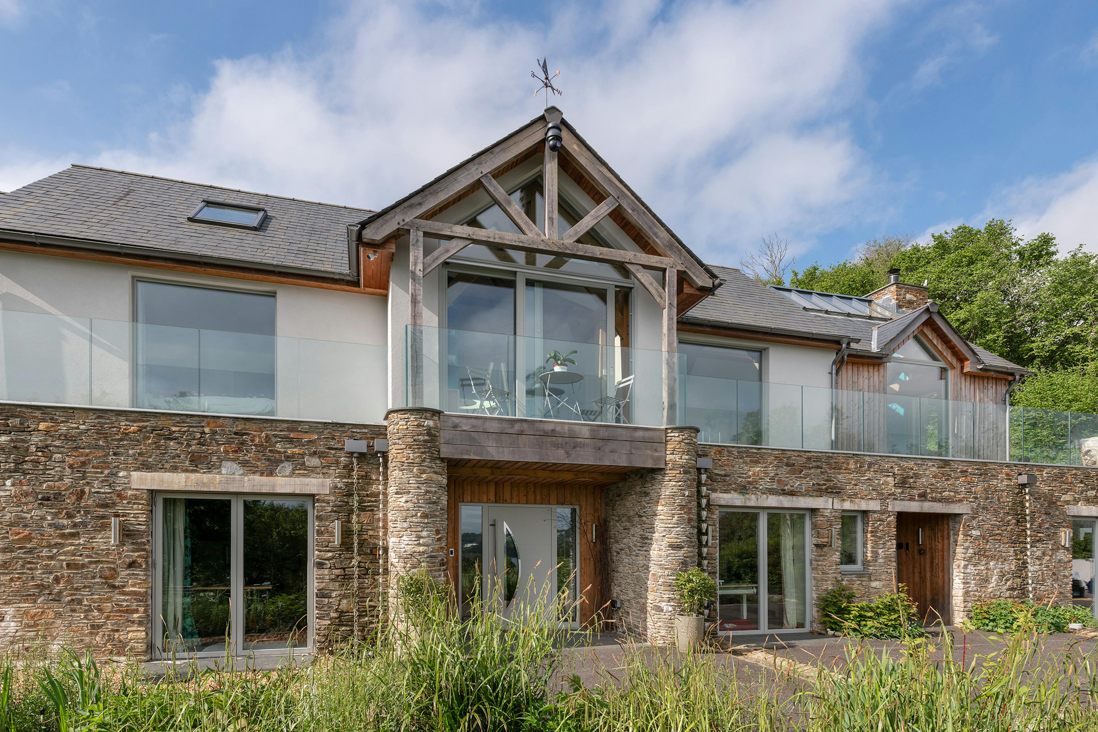 The front view of an oak framed reverse level home with an oak framed balcony and stone cladding on the lower level