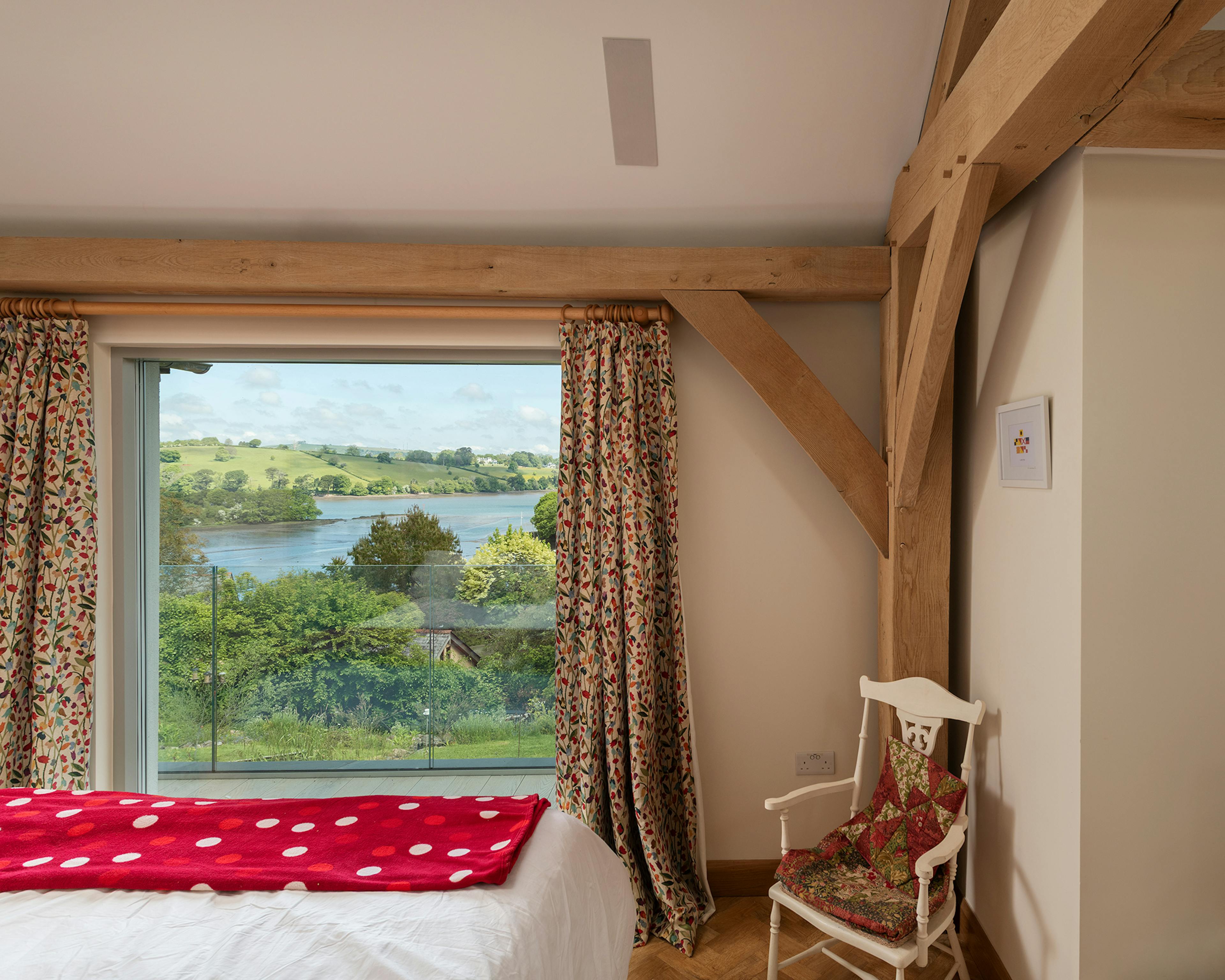 An oak framed bedroom with a window with views of an estuary