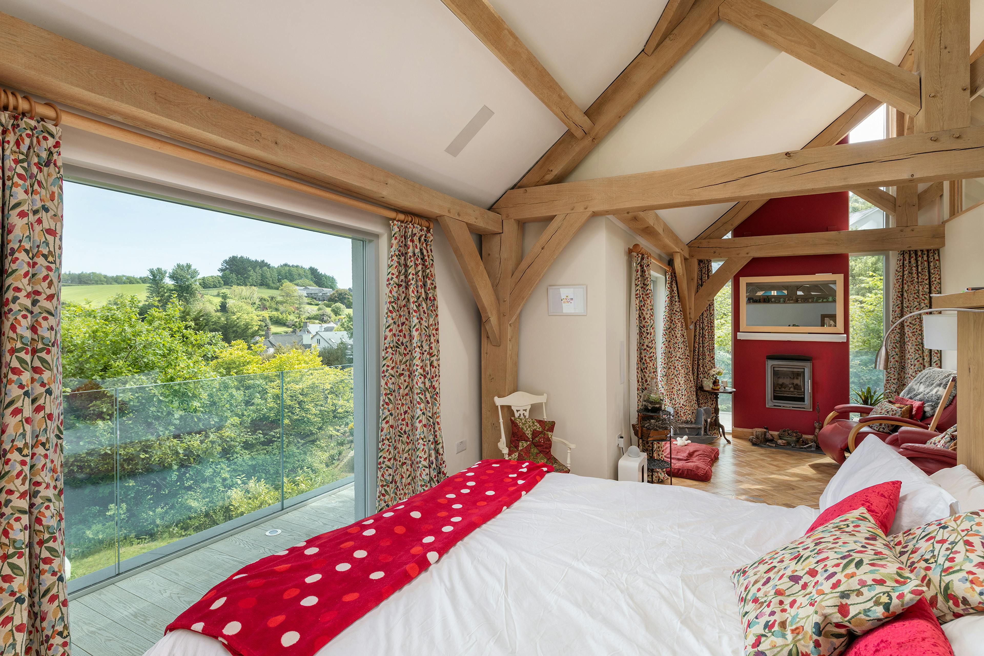 An oak framed bedroom with a window with views of an estuary