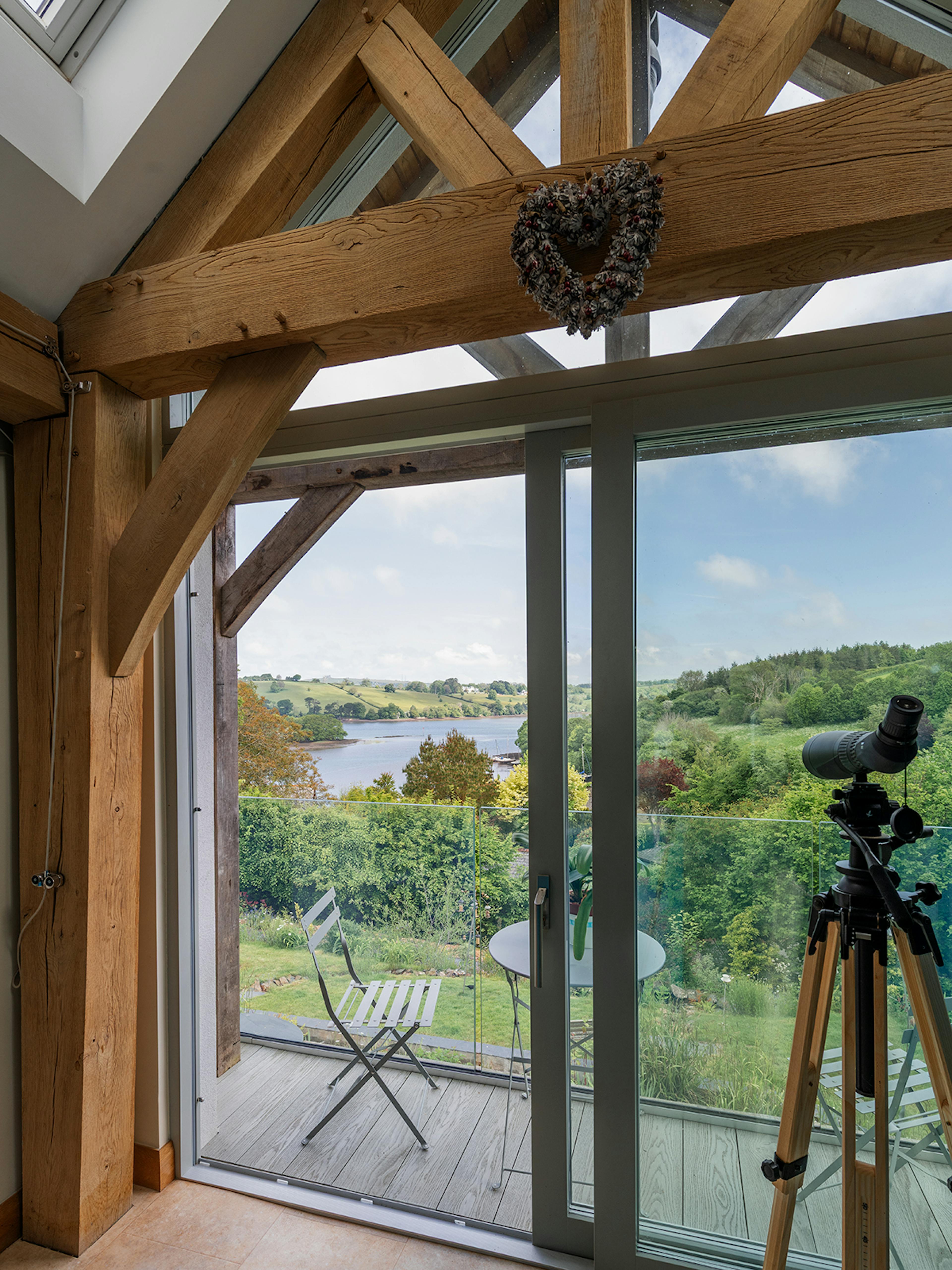 An oak framed living room with views of the estuary and sliding doors to an oak framed balcony
