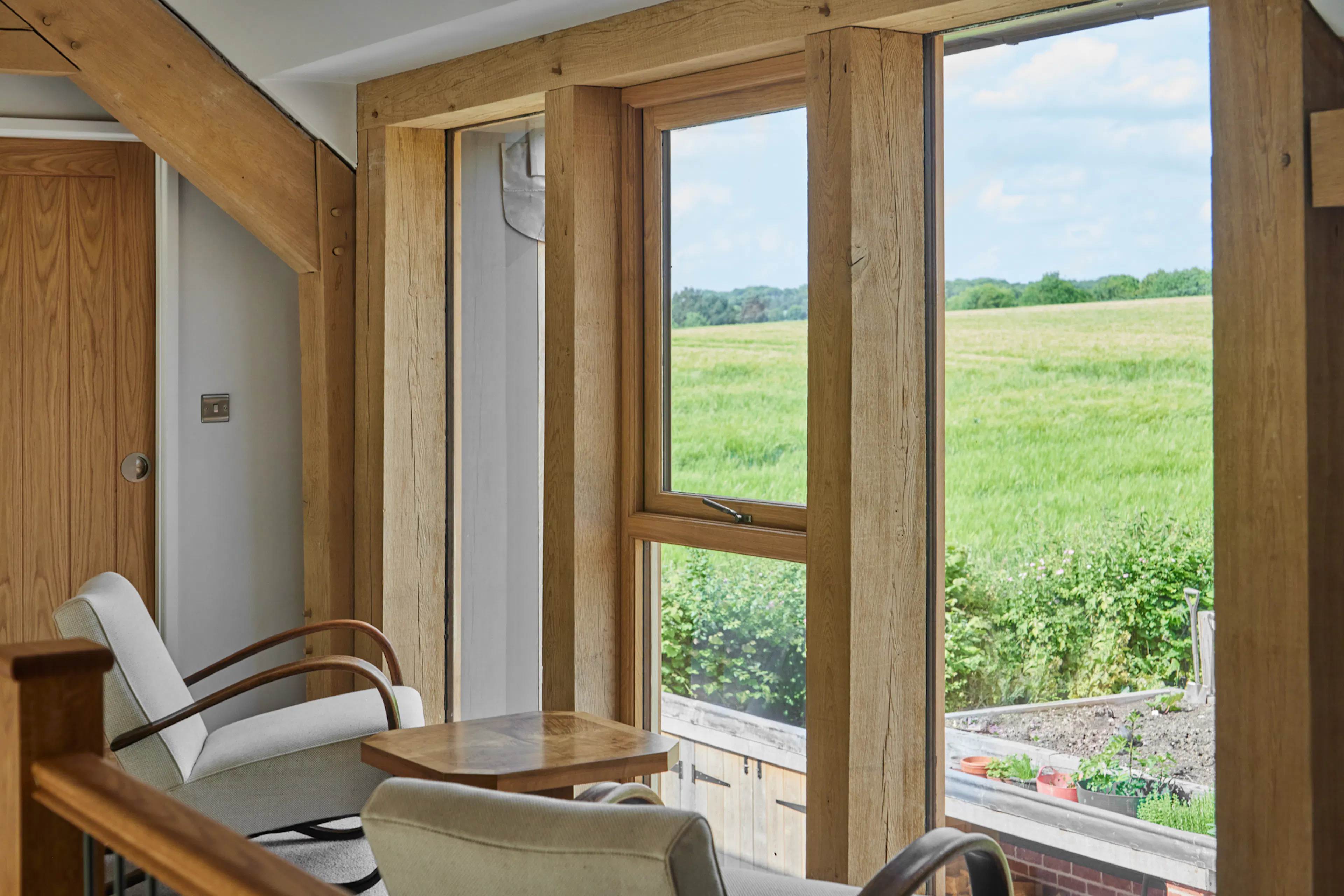 A mezzanine landing area with armchairs in a large oak framed home