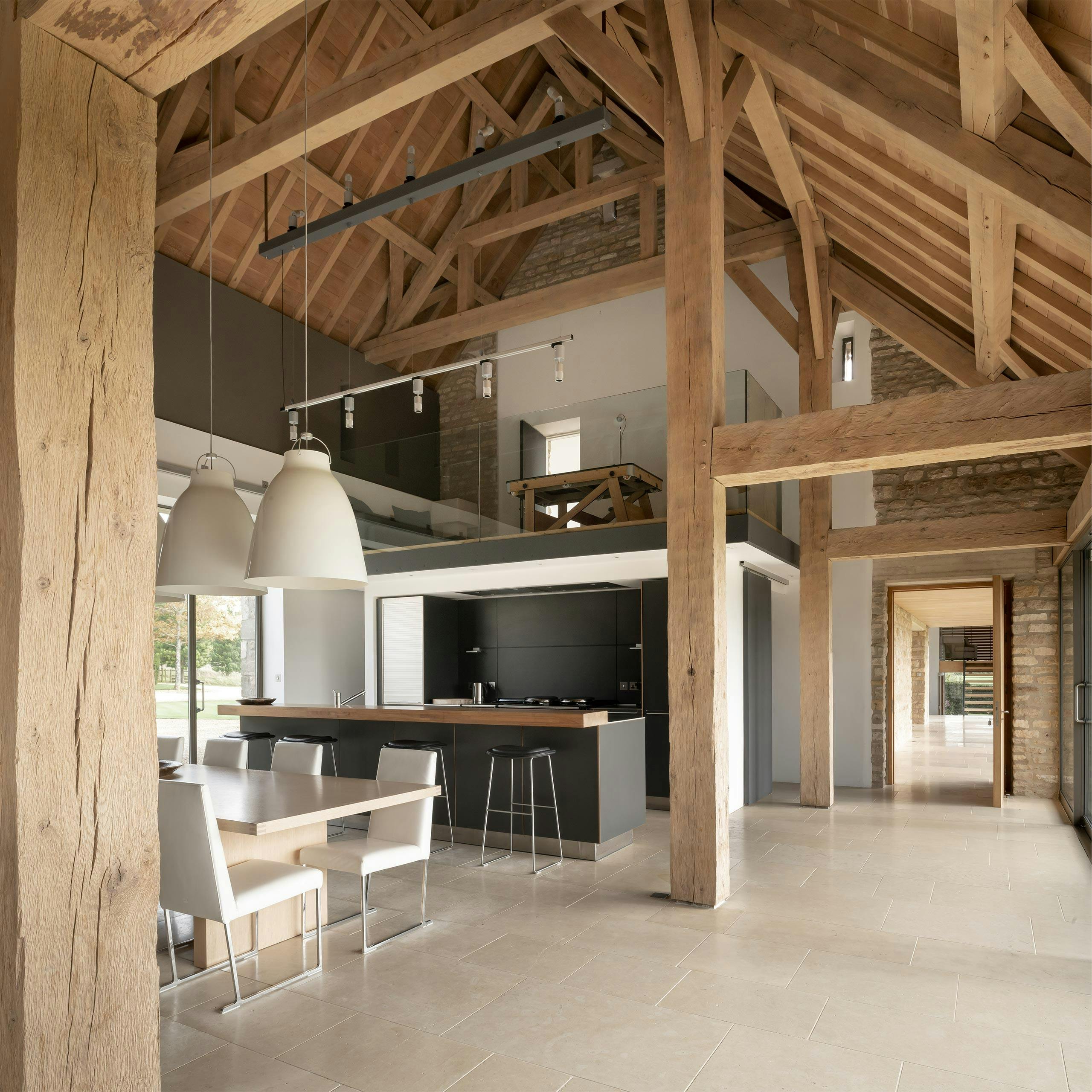 View across a spacious open-plan kitchen-dining room featuring a timber frame, soaring vaulted ceilings, and timber wall and ceiling boarding