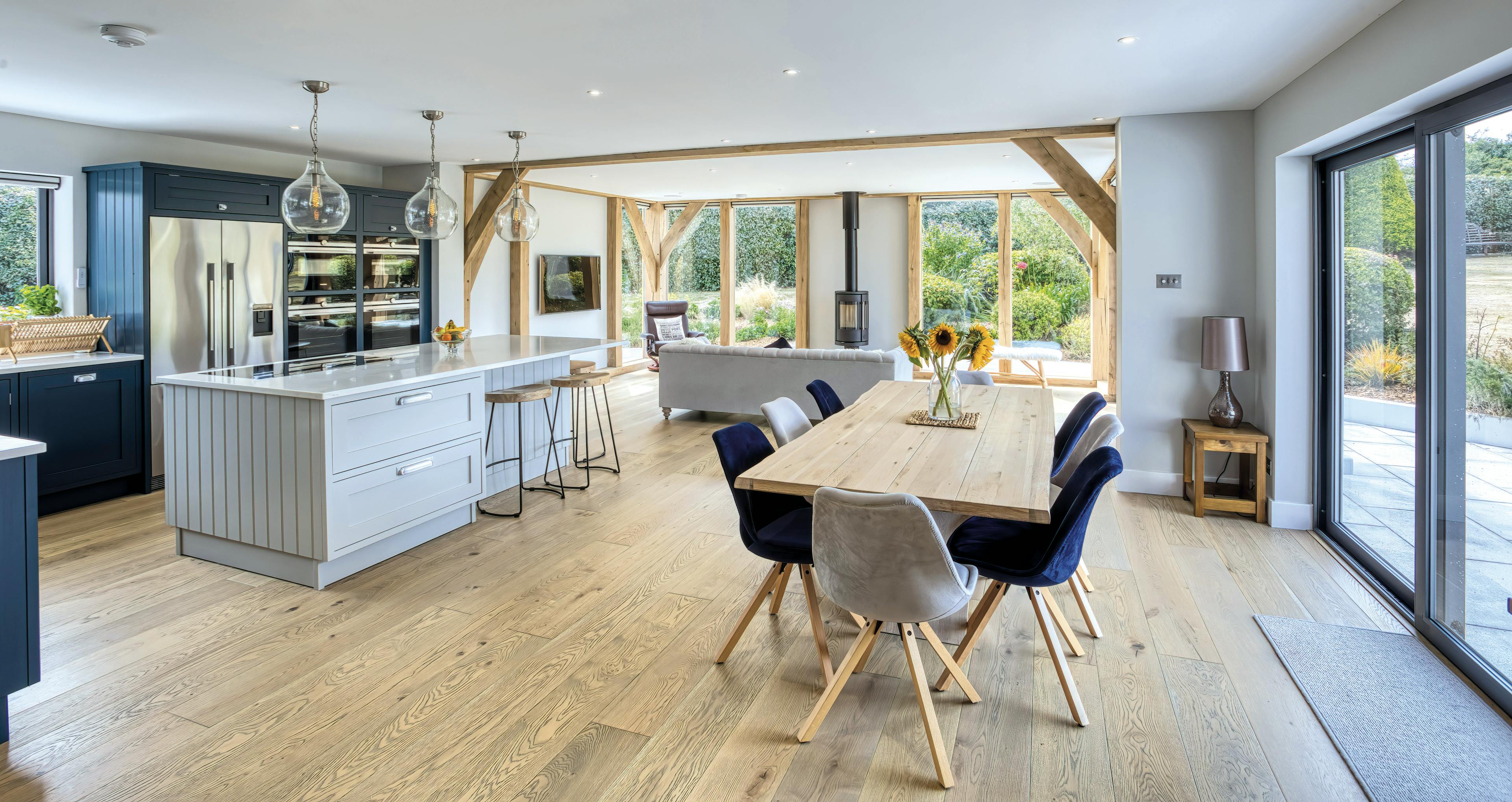 Interior view of the Mont Hubert oak frame extension, featuring an open-plan kitchen and dining area with extensive glazing that floods the space with natural light.