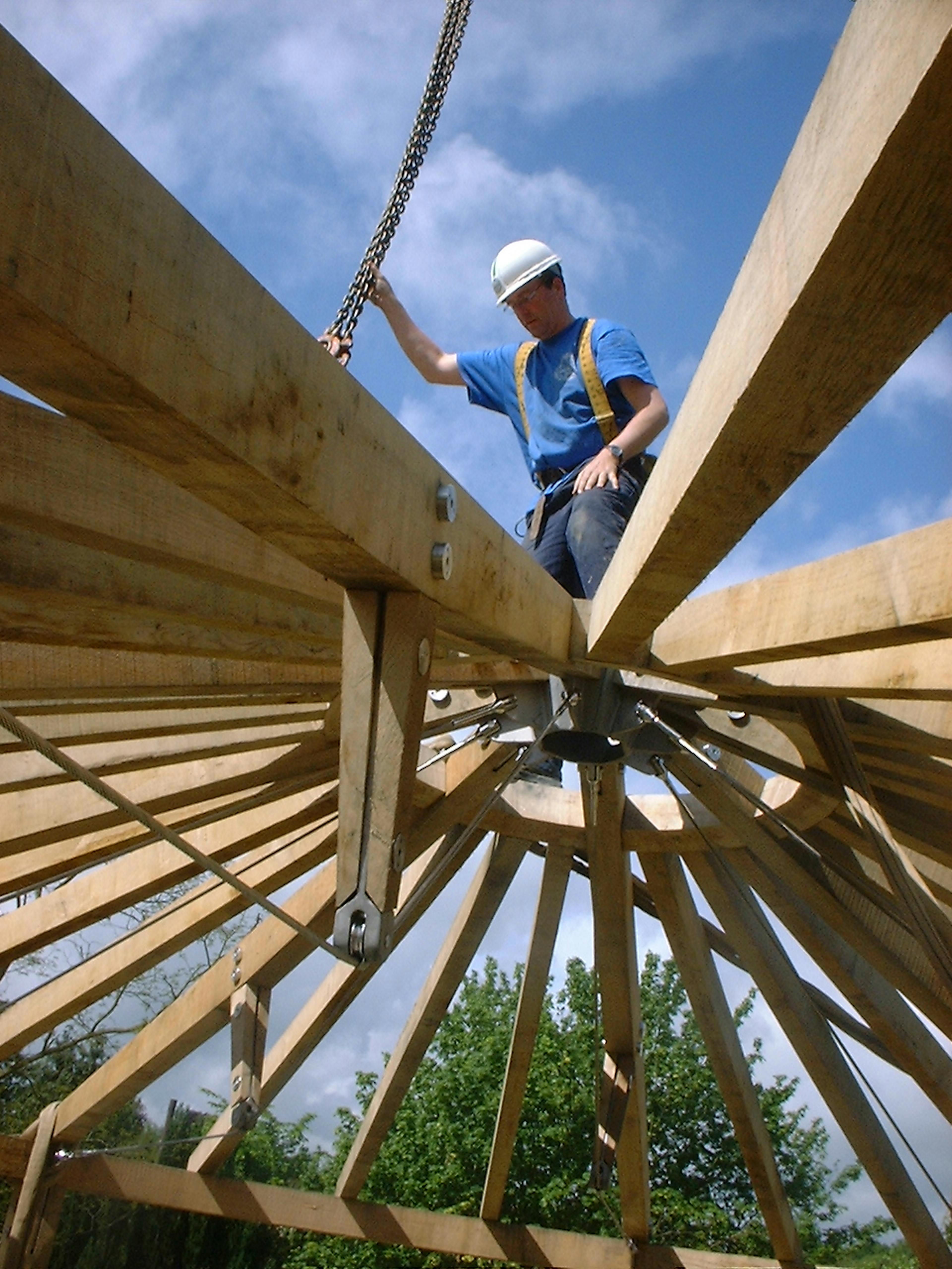 Photo of a Carpenter on site at the oak frame construction, standing beside the timber structure during assembly