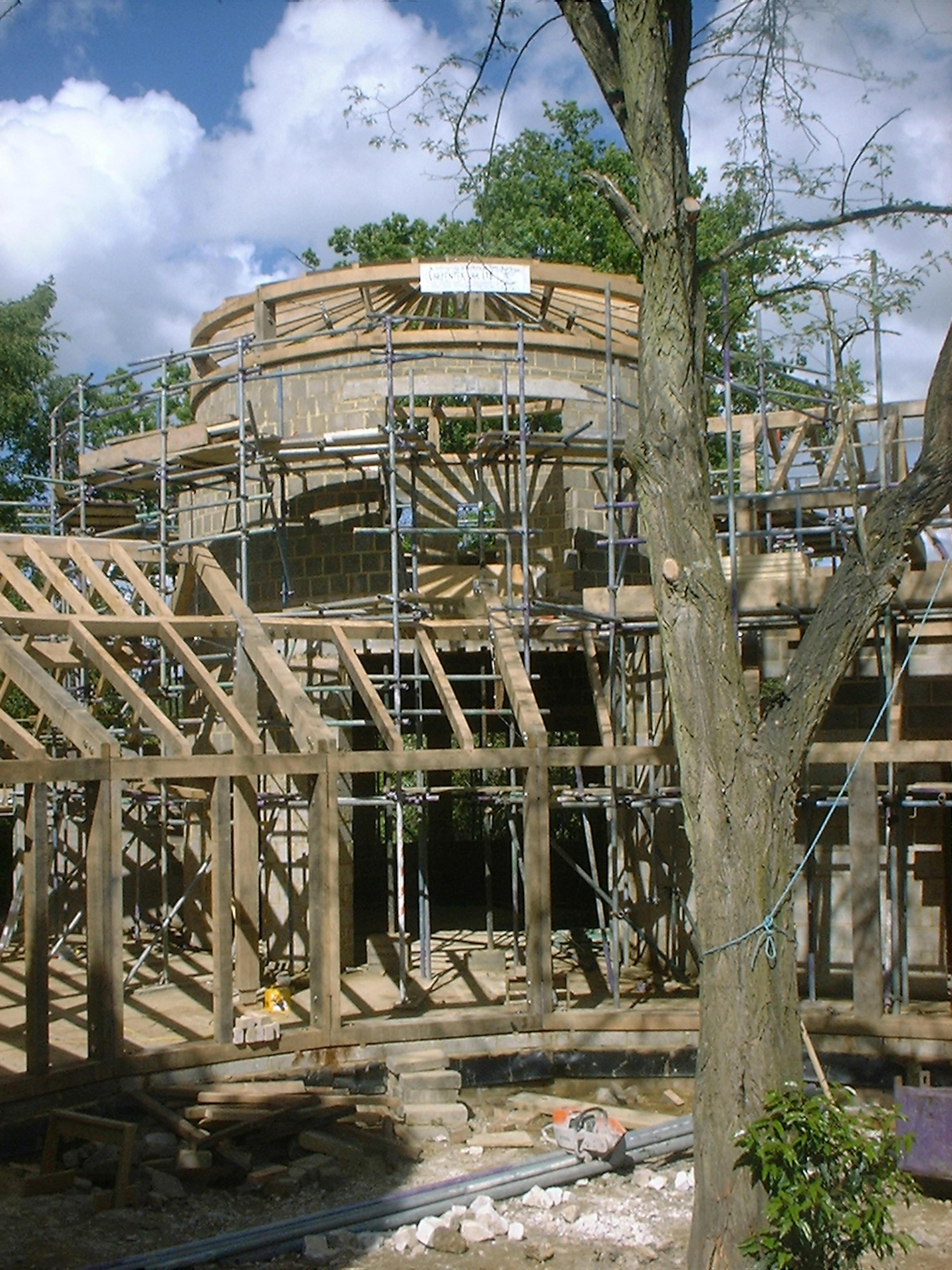 Partially assembled oak timber frame structure on a construction site, showing exposed beams and framework in progress