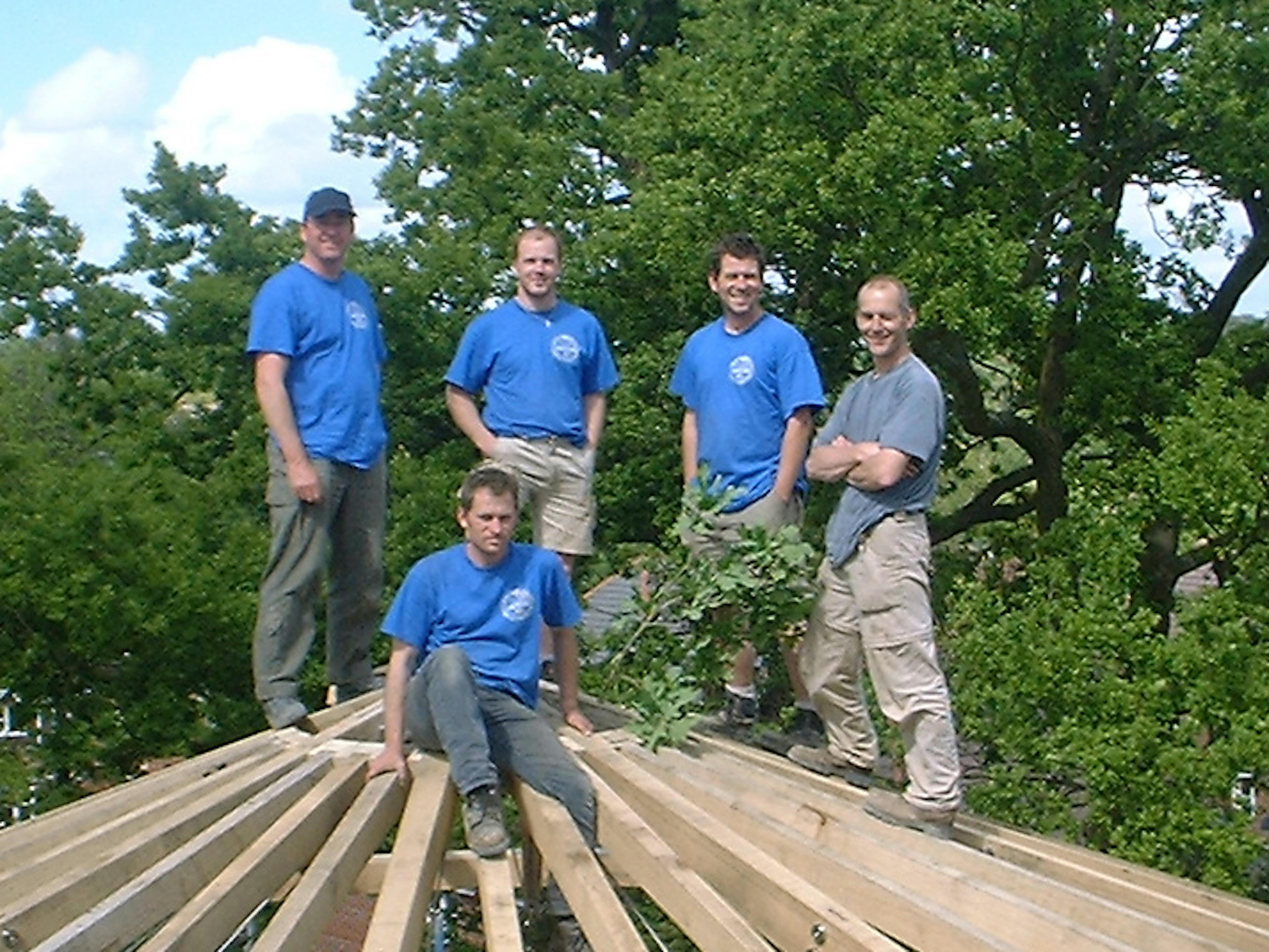 Team of workers assembling an oak timber frame structure on a construction site, actively collaborating on site tasks