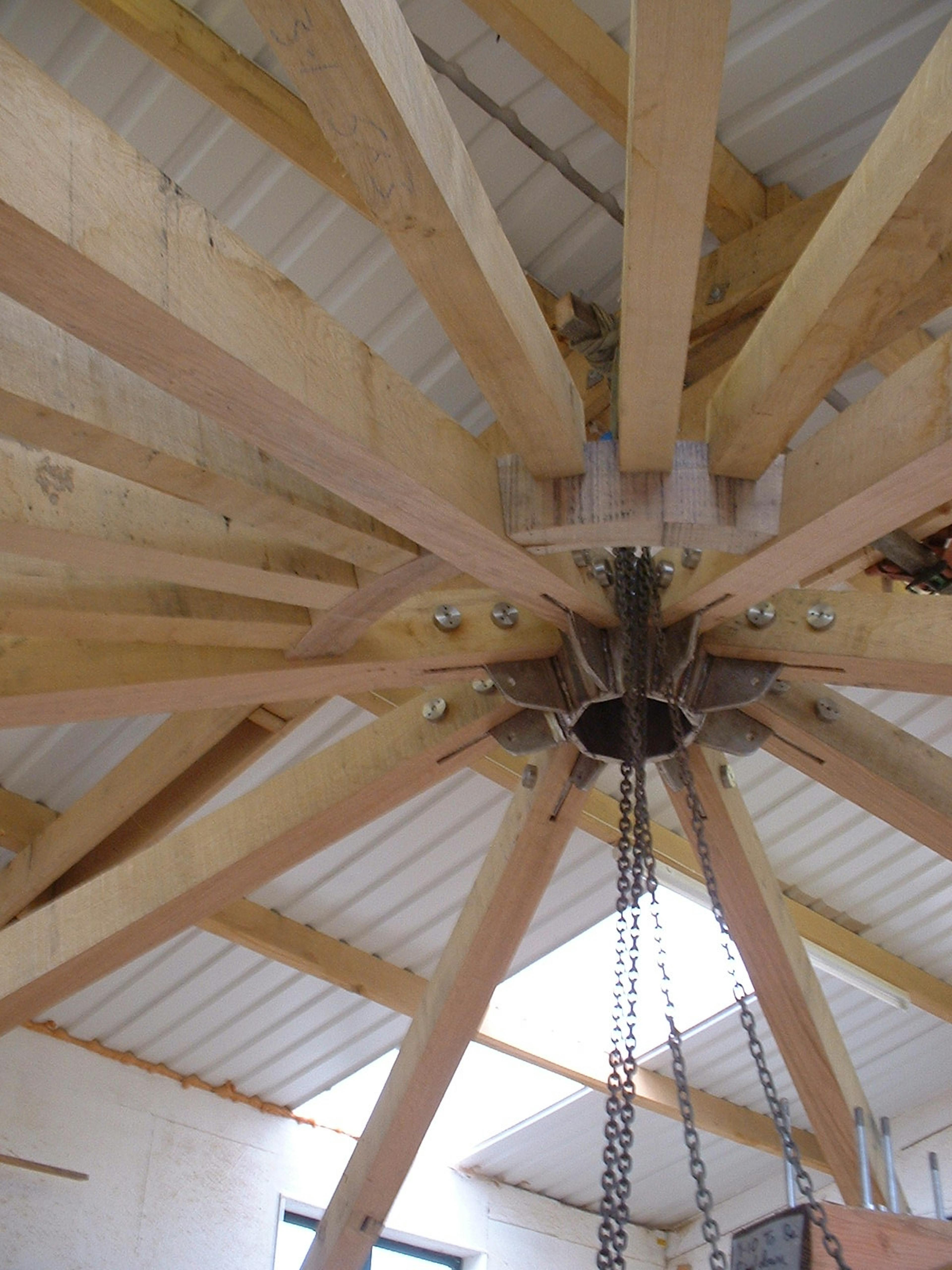 Close-up of roof detail assembly in a workshop, showing timber beams and joinery being fitted together during construction