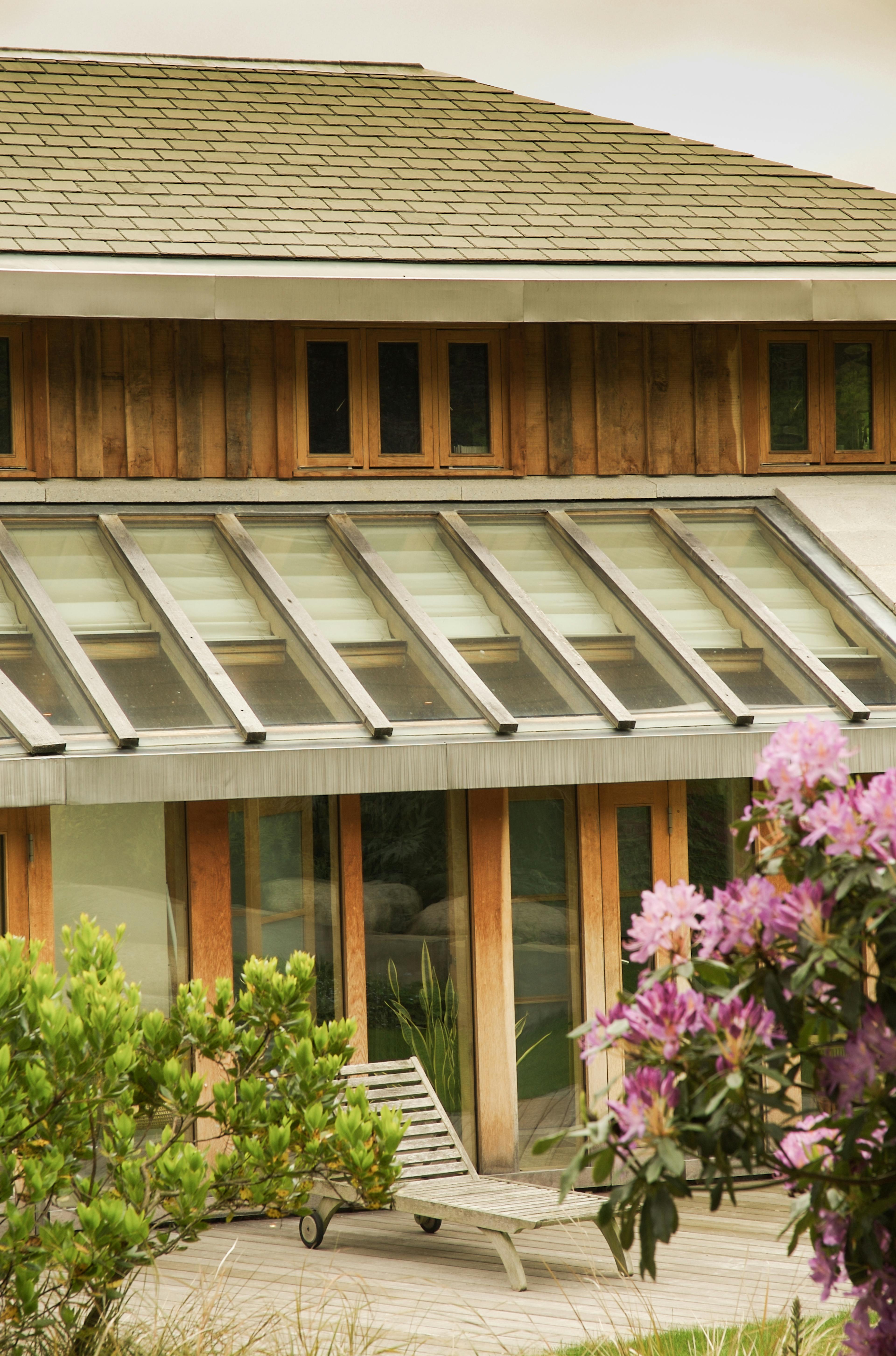 Exterior view of an oak-framed house showing a covered walkway with timber cladding, featuring natural materials and craftsmanship integrated into the architectural design